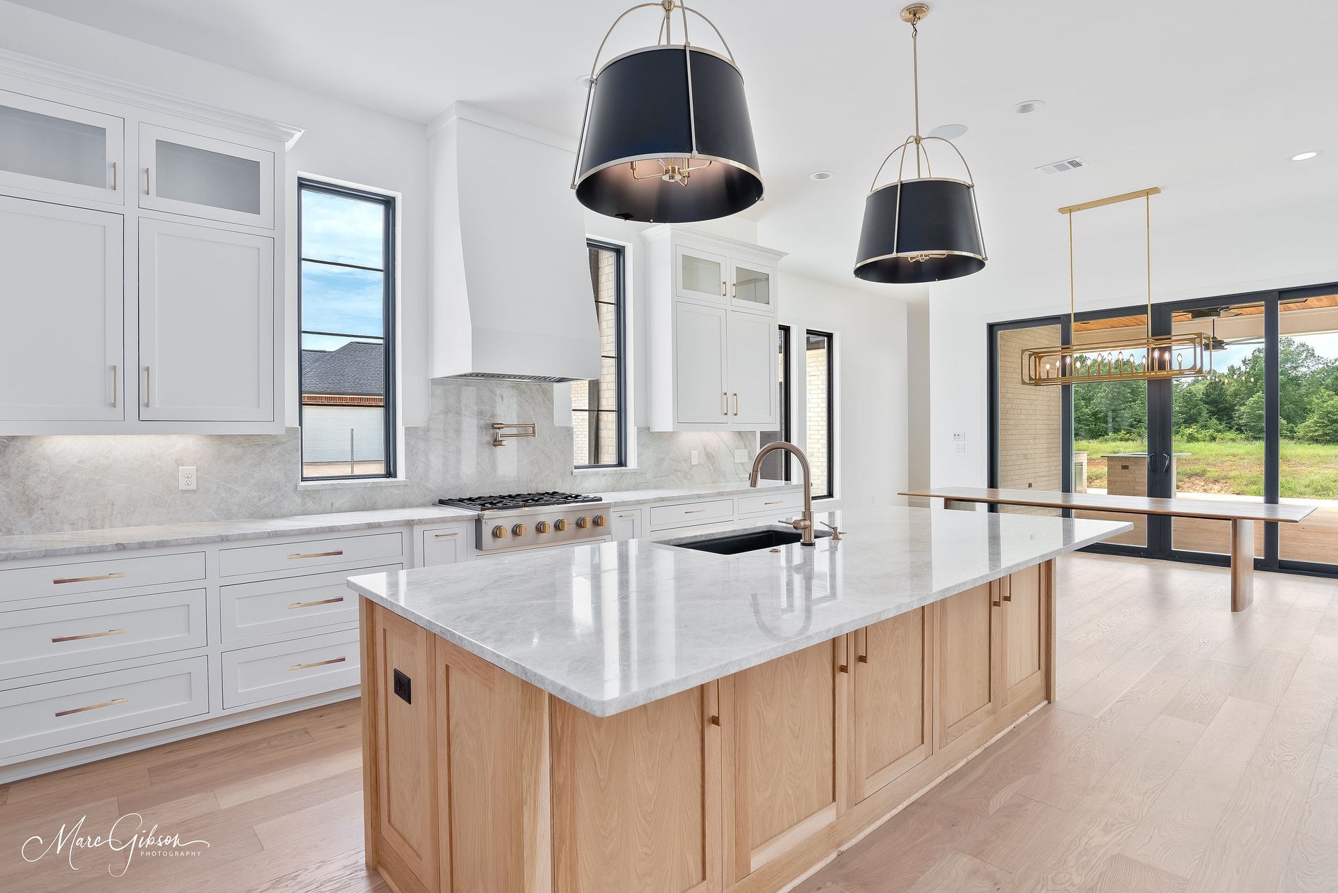 Modern kitchen with white and wood cabinets, island, and large windows.