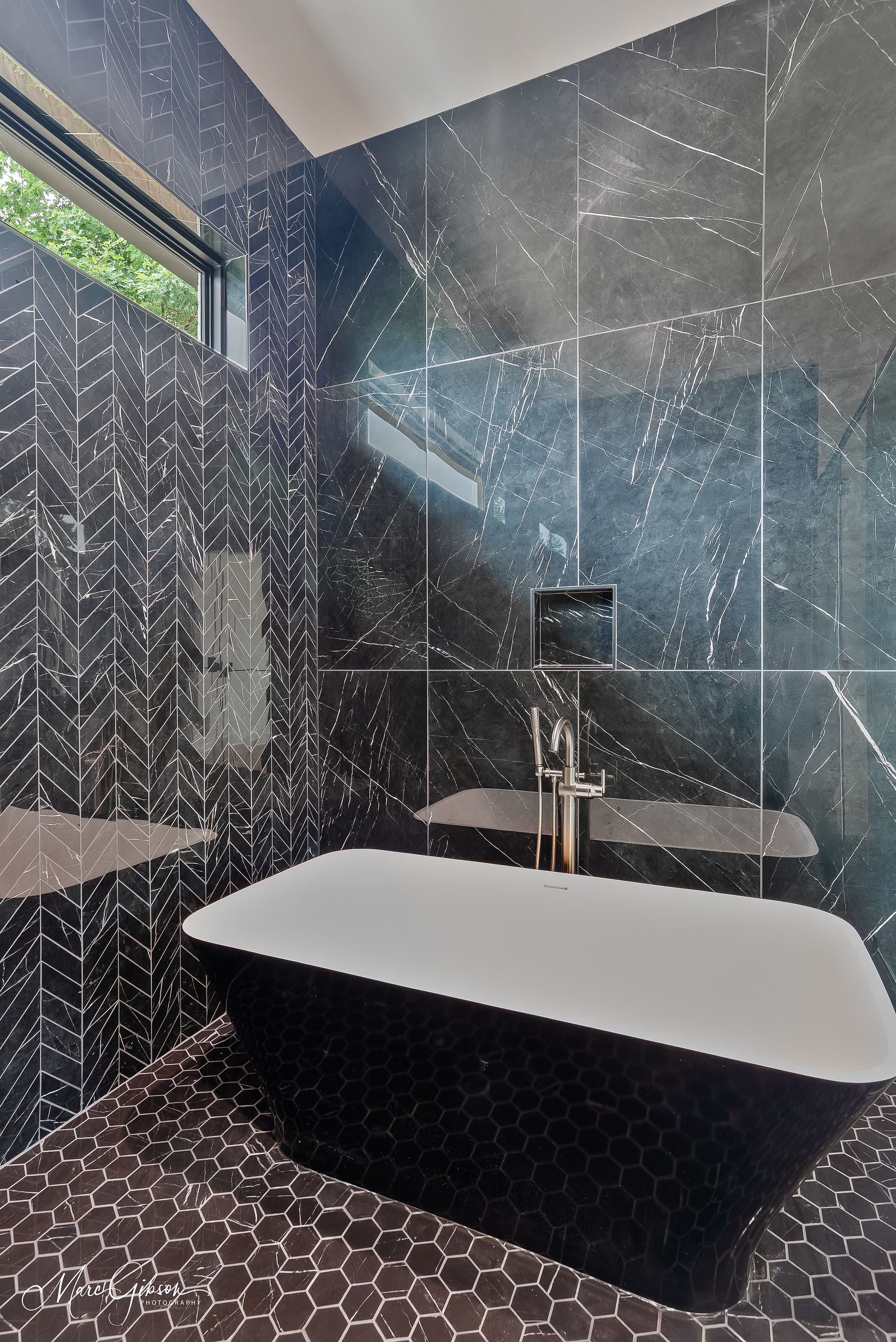Luxurious black and white bathroom with a clawfoot tub and dark tiled walls.
