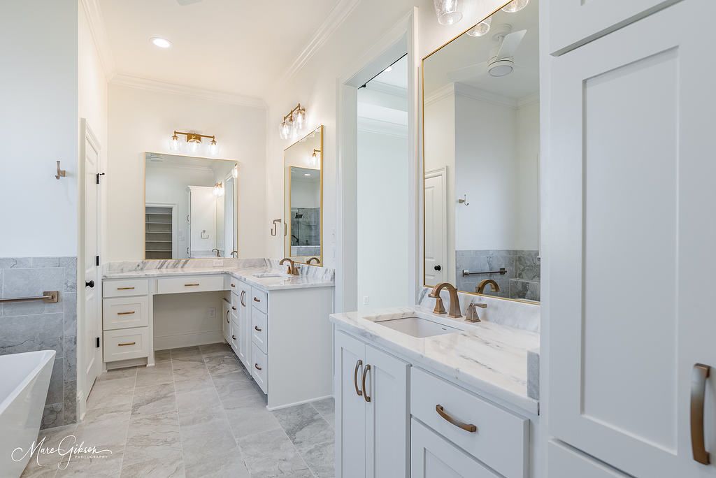 Spacious white bathroom with marble countertops, double sinks, and large mirrors.