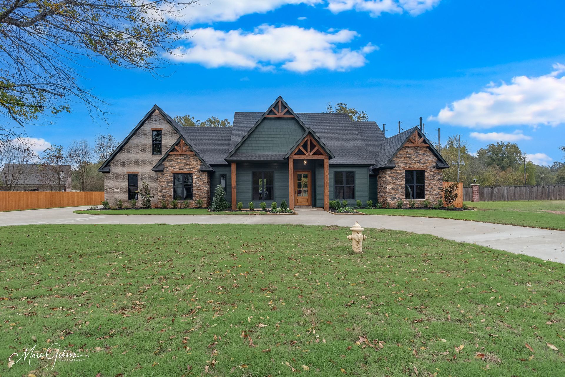 A large brick and stone home with a green roof and blue sky.