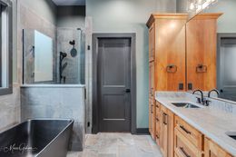 Bathroom with a dark gray door, light wood cabinets, and a black bathtub.
