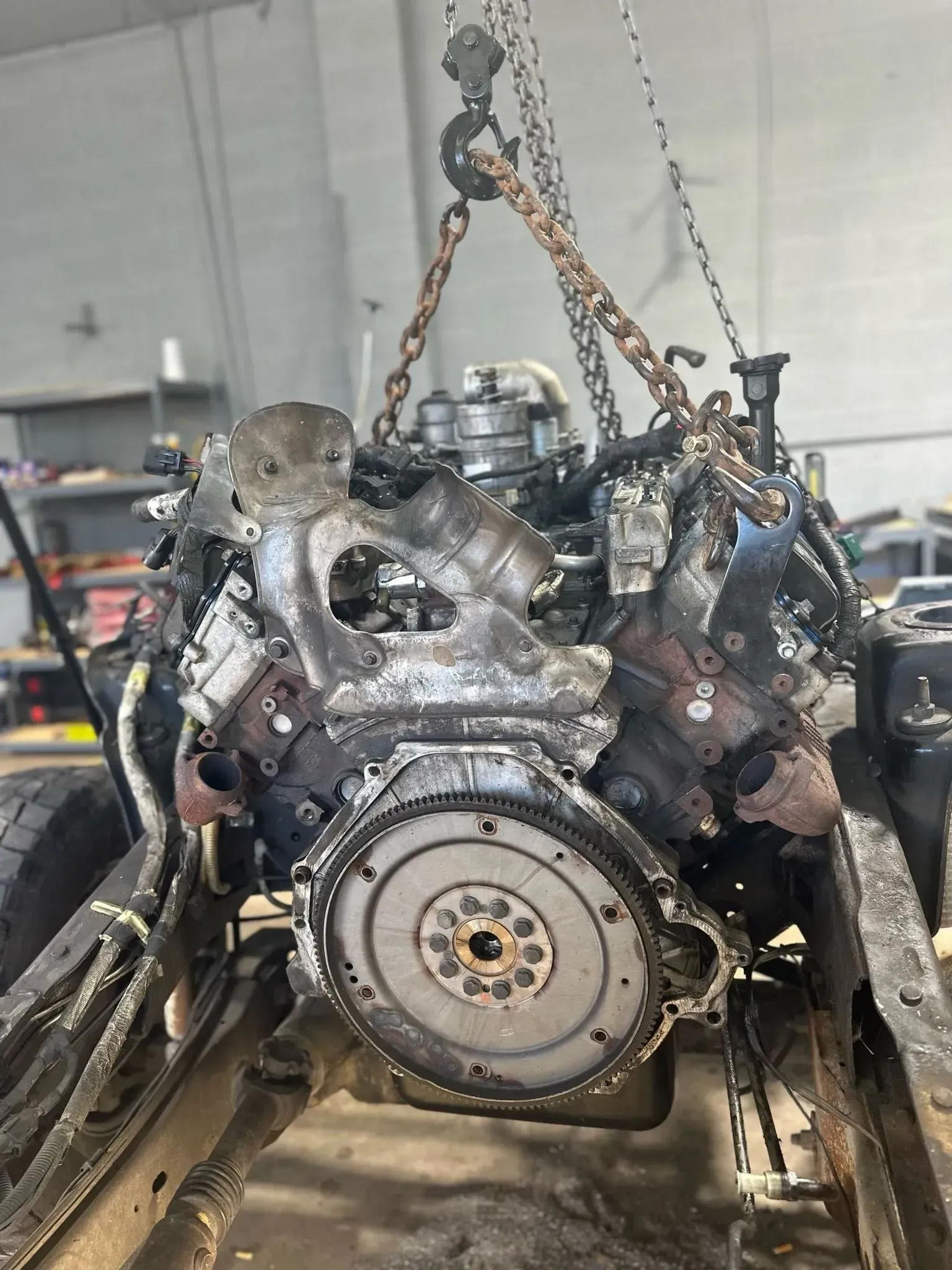 A car engine is being lifted by chains in a garage.