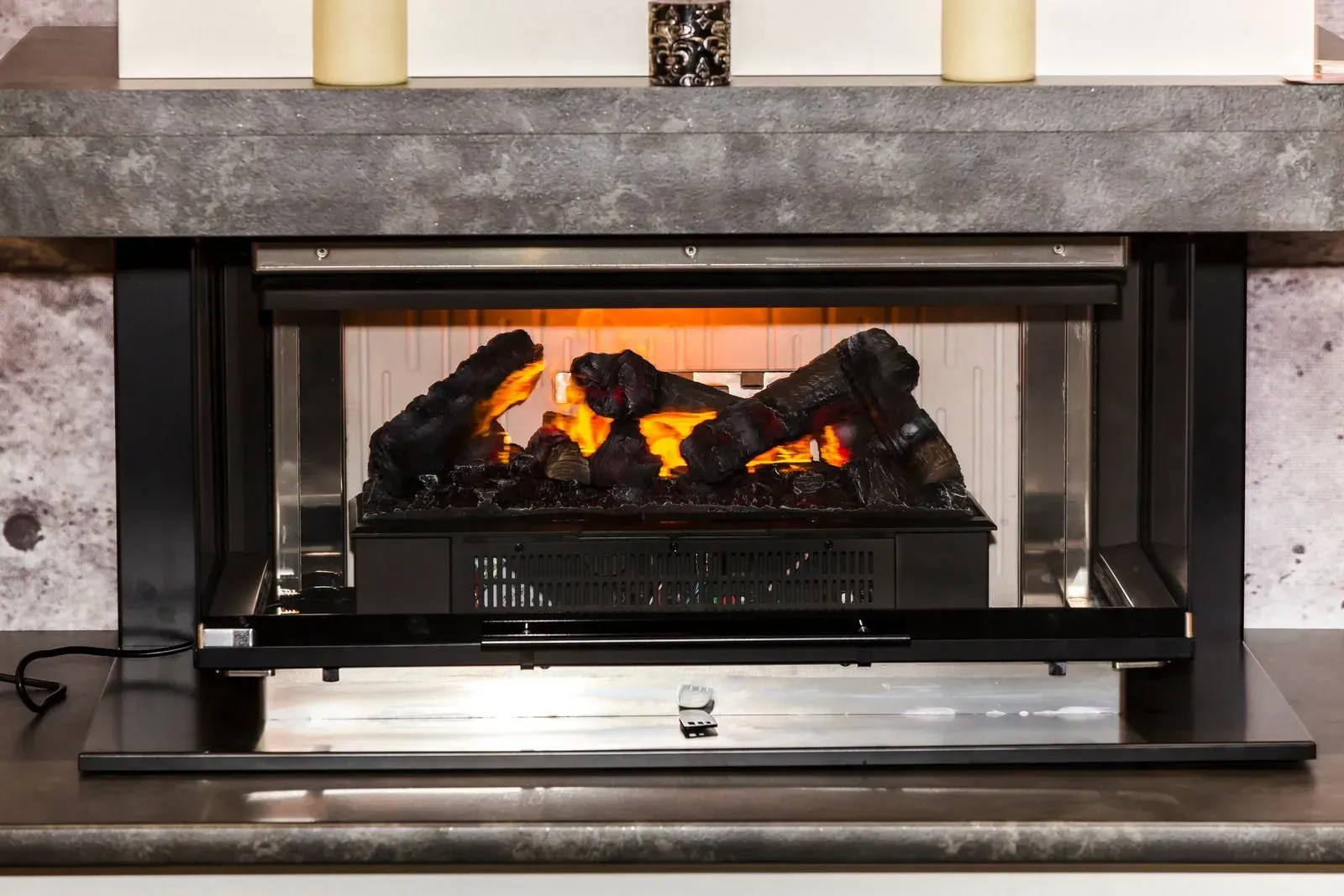 A fireplace with a lot of logs in it and candles in the background.