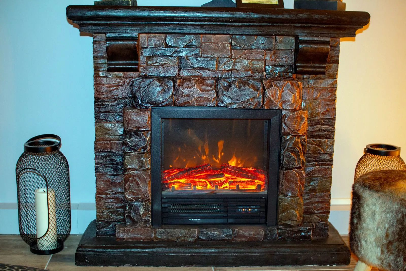 Fireplace with stone facade, glowing flame effect, flanked by decorative lanterns.