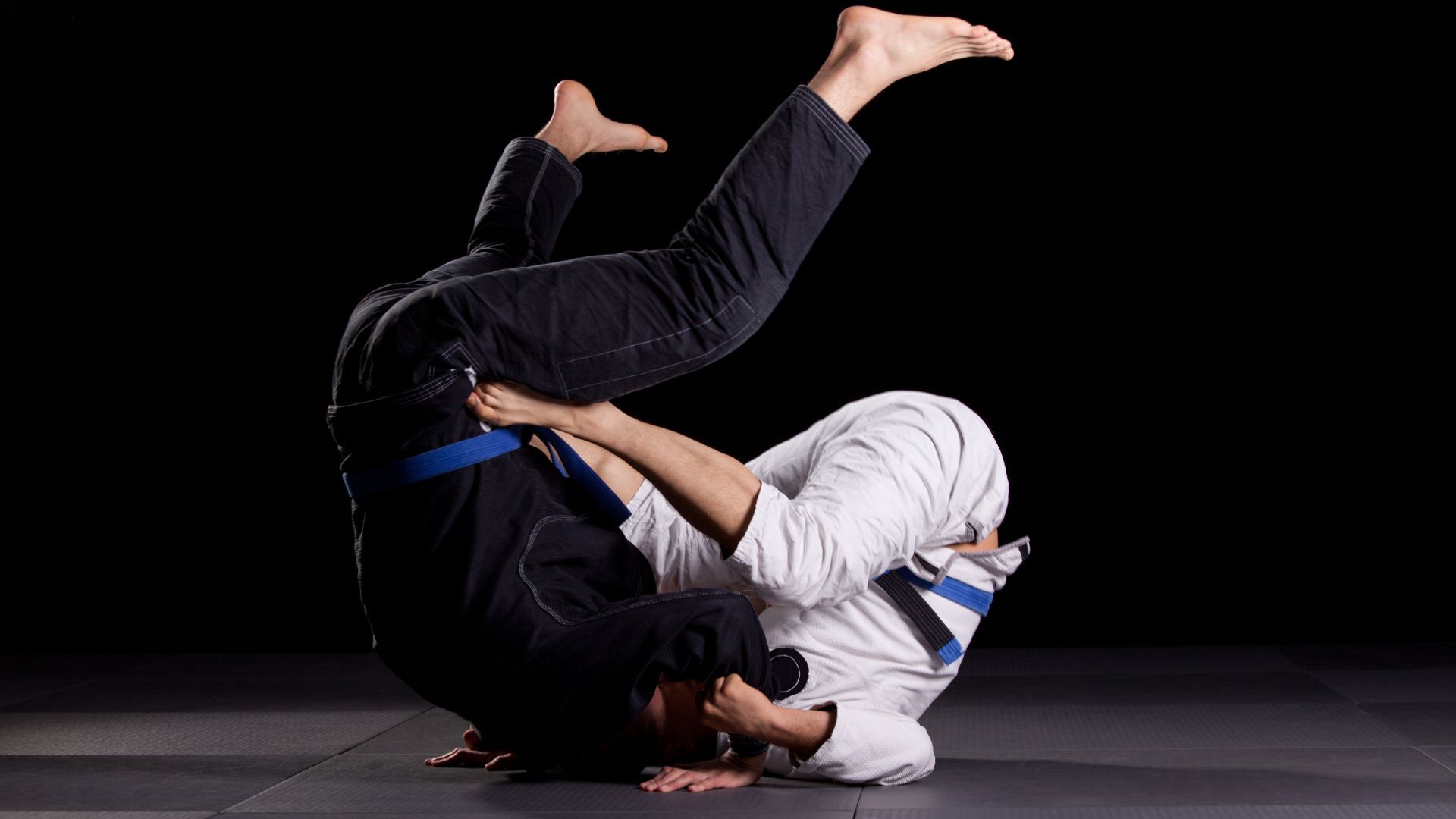 Two people are doing a jiu jitsu move on a mat.
