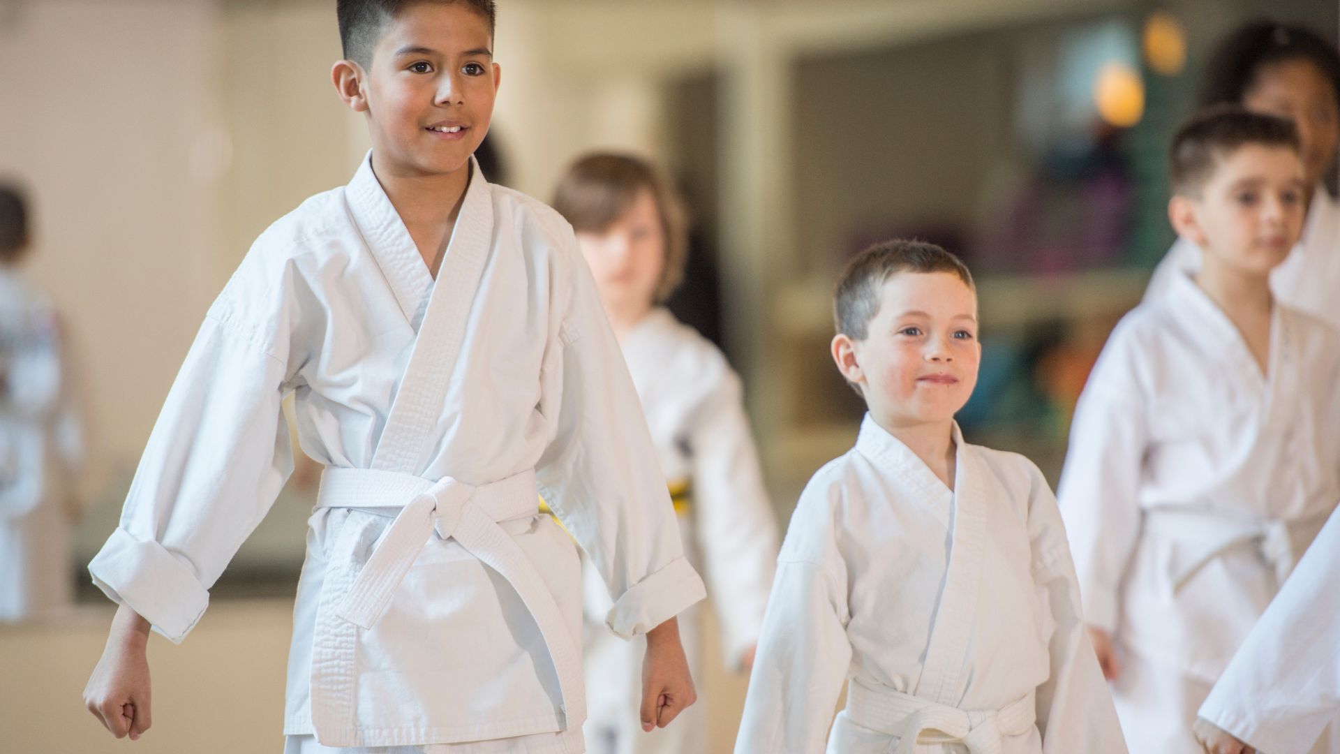 A group of young kids are practicing karate in a gym.