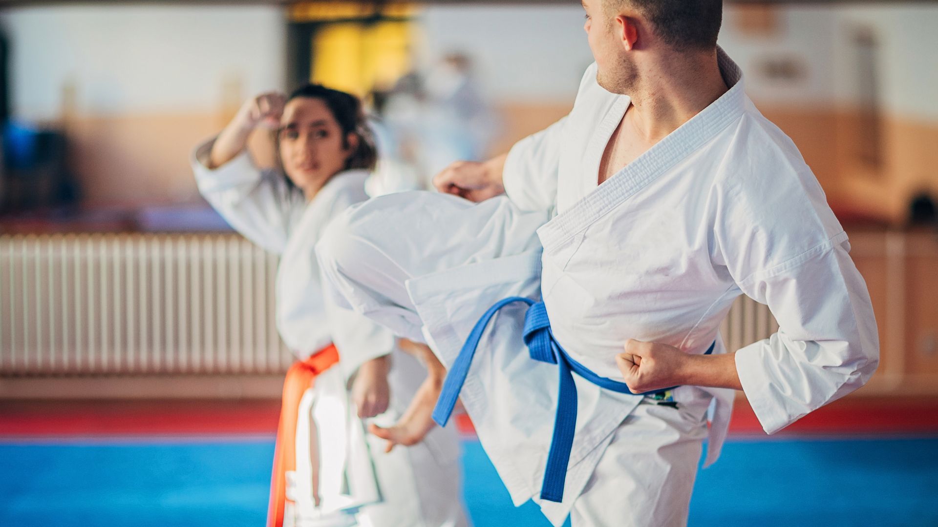 A man and a woman are practicing kickboxing in a gym.