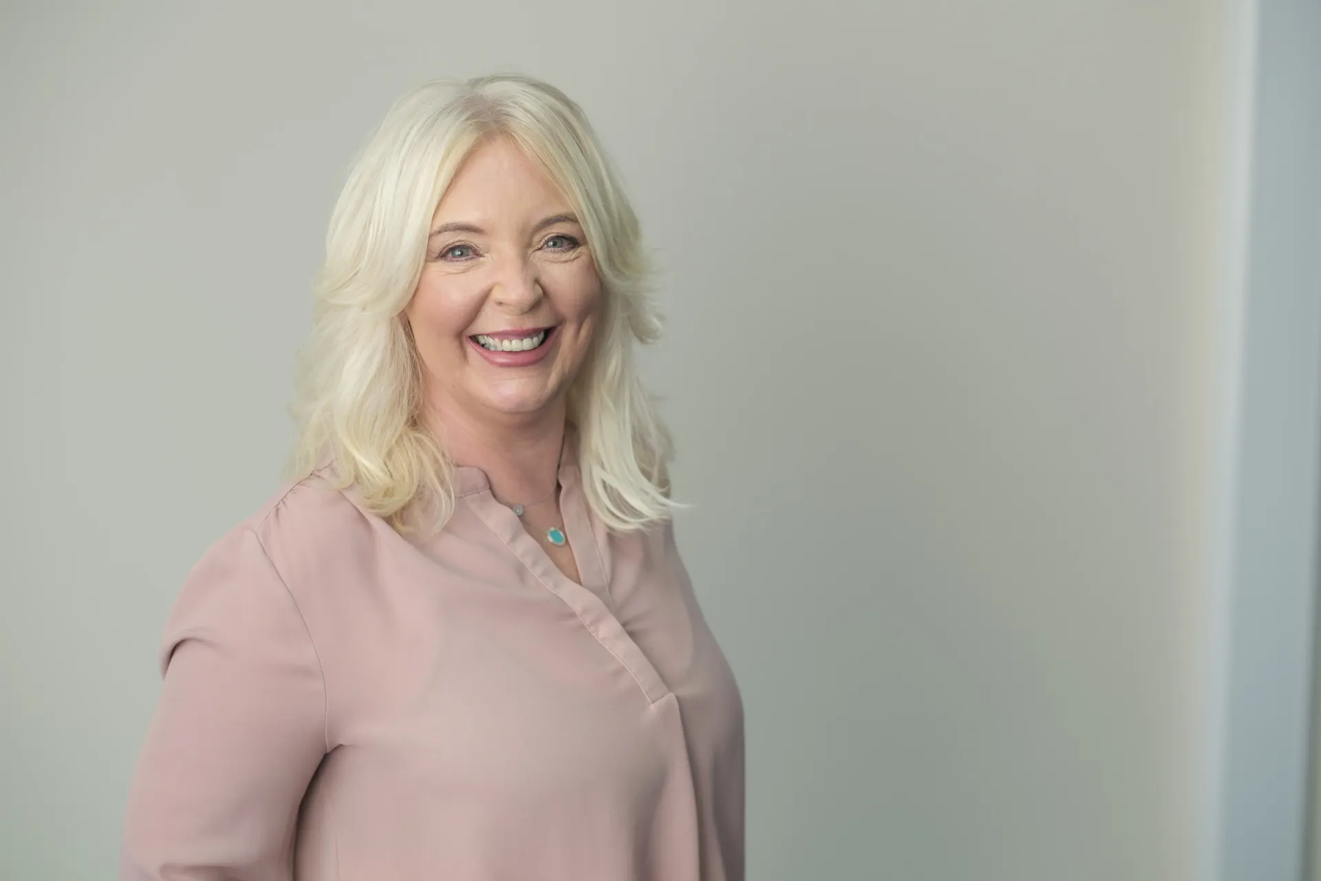 A woman with blonde hair is wearing a green and blue floral shirt.