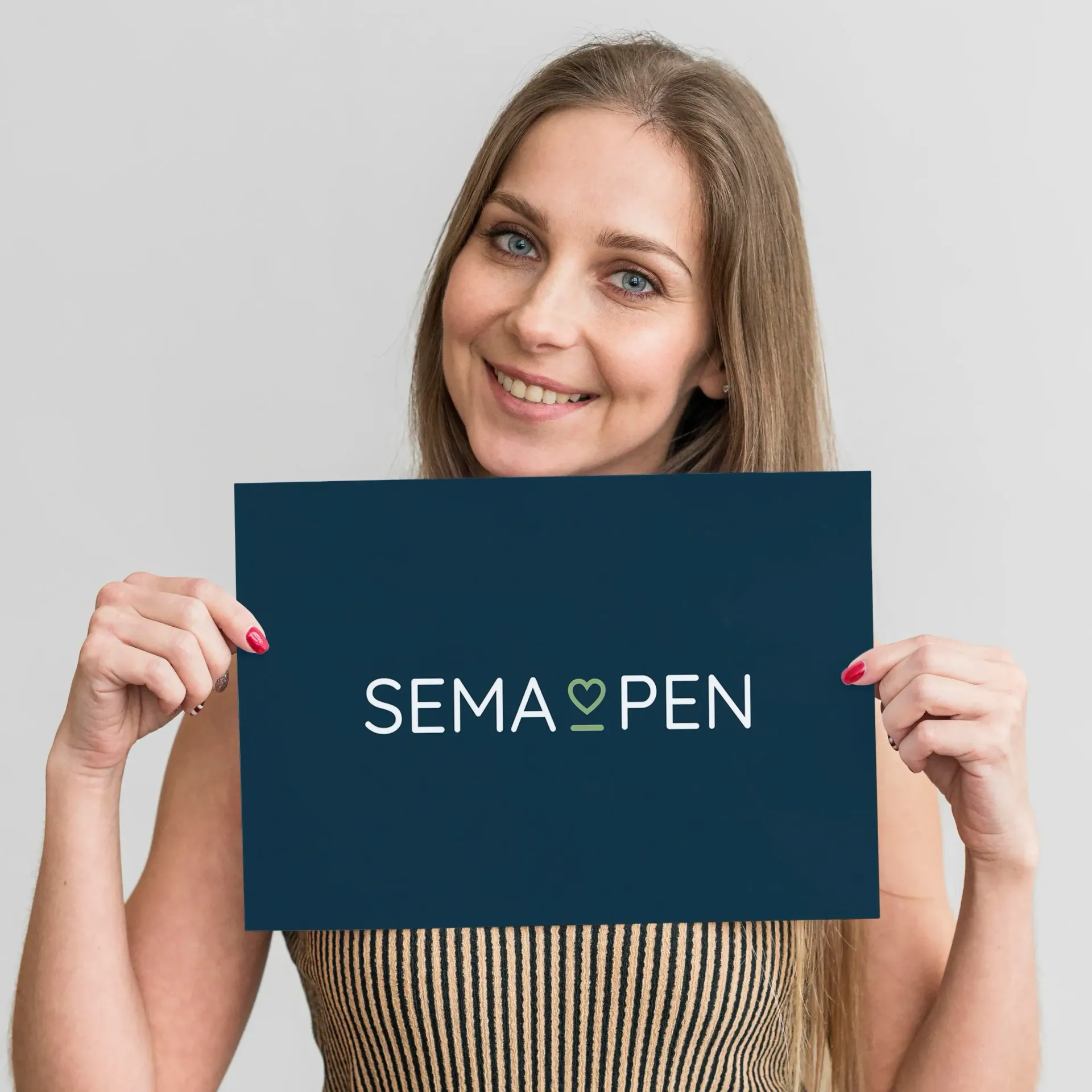 A lady is holding a sign that says SemaPen. She has a warm smile on her face.