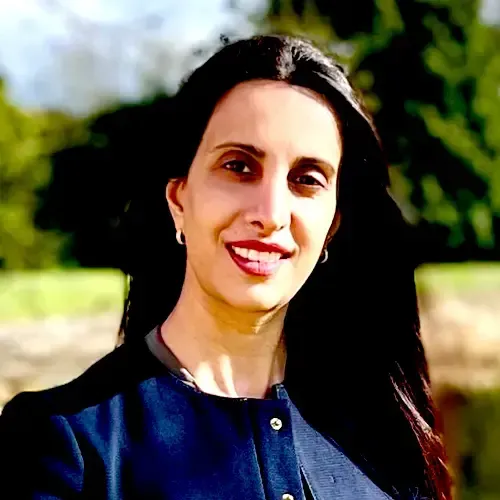 A woman in a black jacket is smiling for the camera.