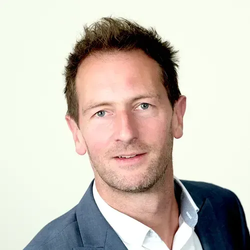 A man in a suit and white shirt is smiling for the camera.