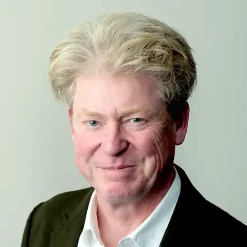 A man wearing glasses and a blue shirt is looking at the camera