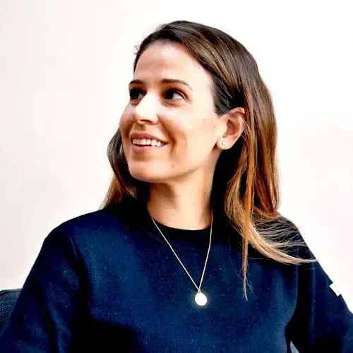 A woman wearing a black shirt and a gold necklace smiles