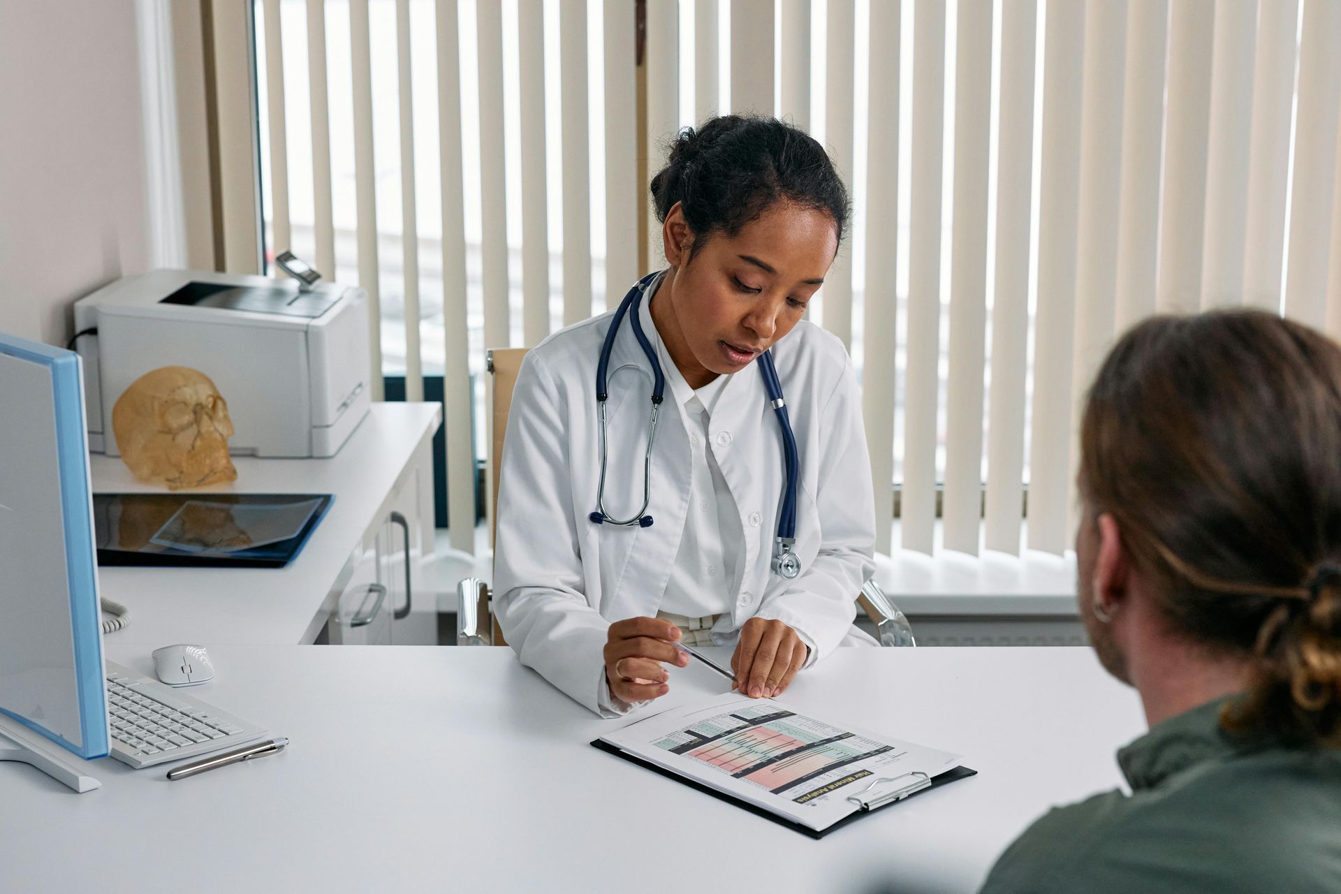 A doctor is sitting at a desk talking to a patient.