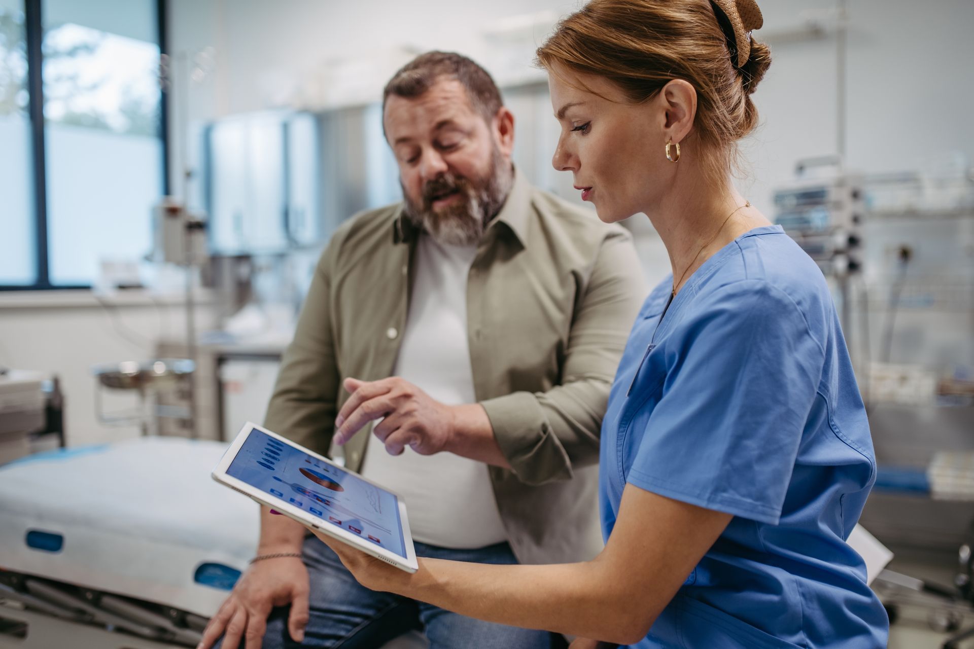 A nurse is looking at a tablet with a patient.