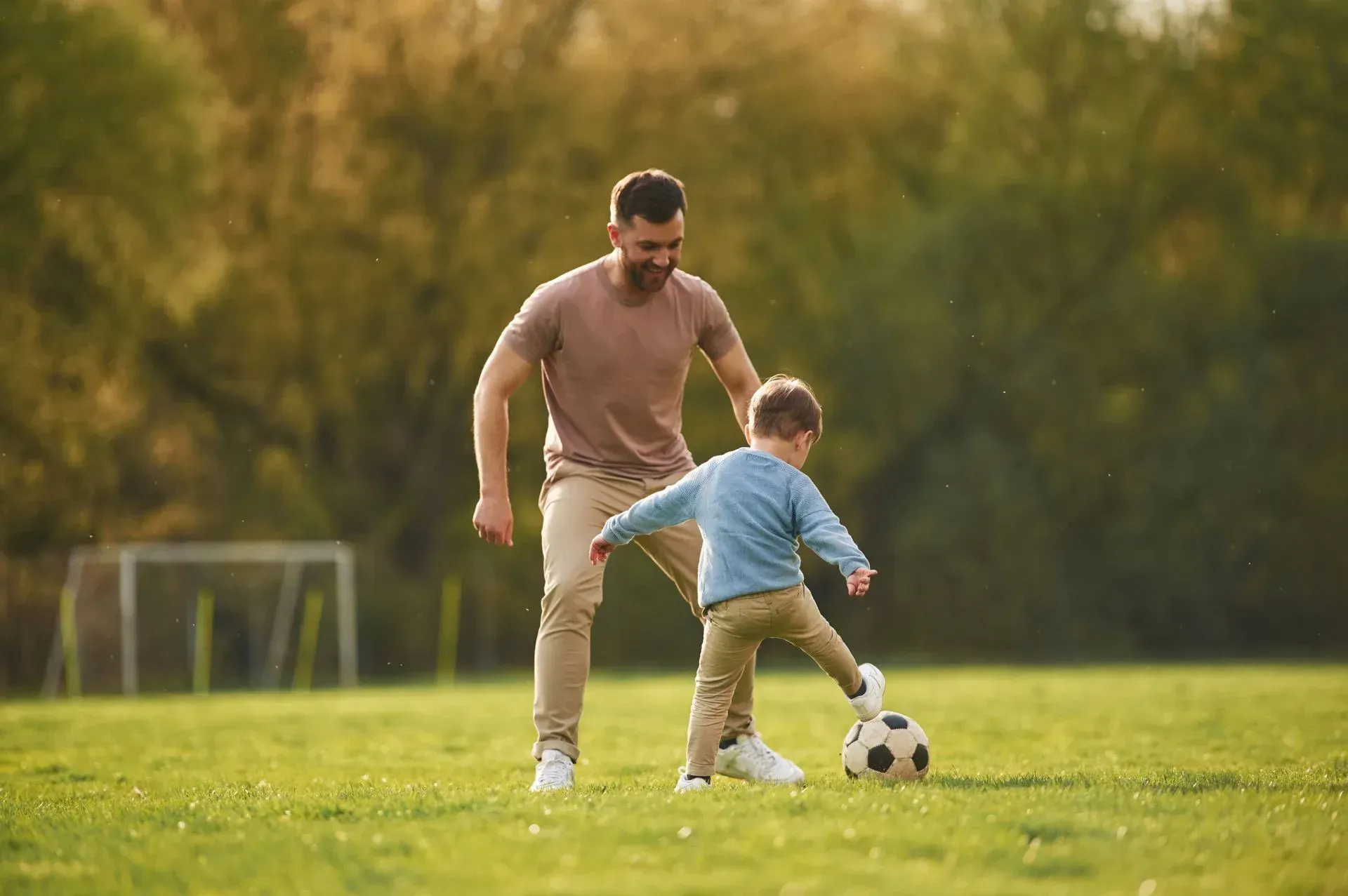 A man and a boy are playing soccer on a field.