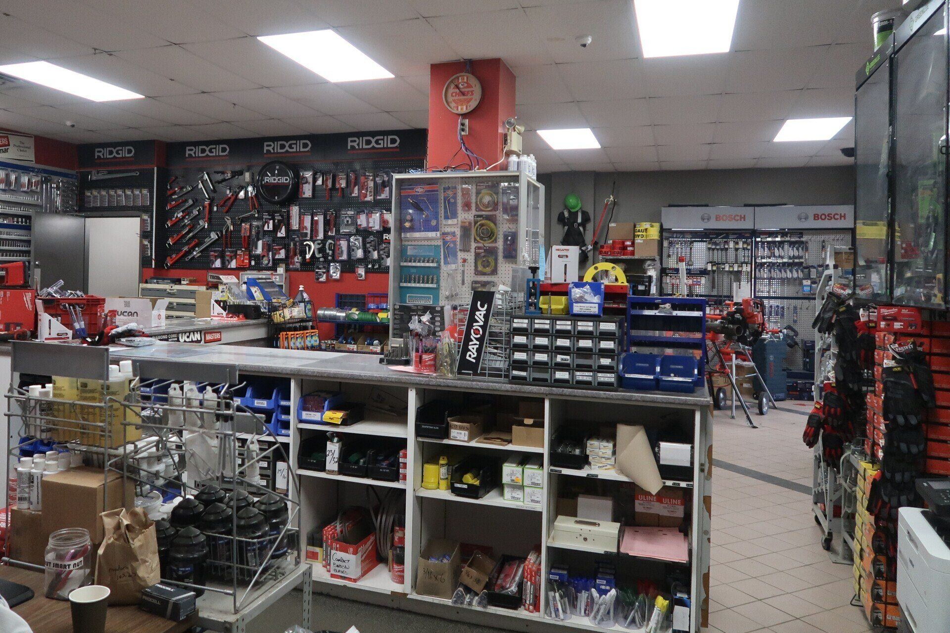 The inside of a hardware store with a clock on the ceiling.