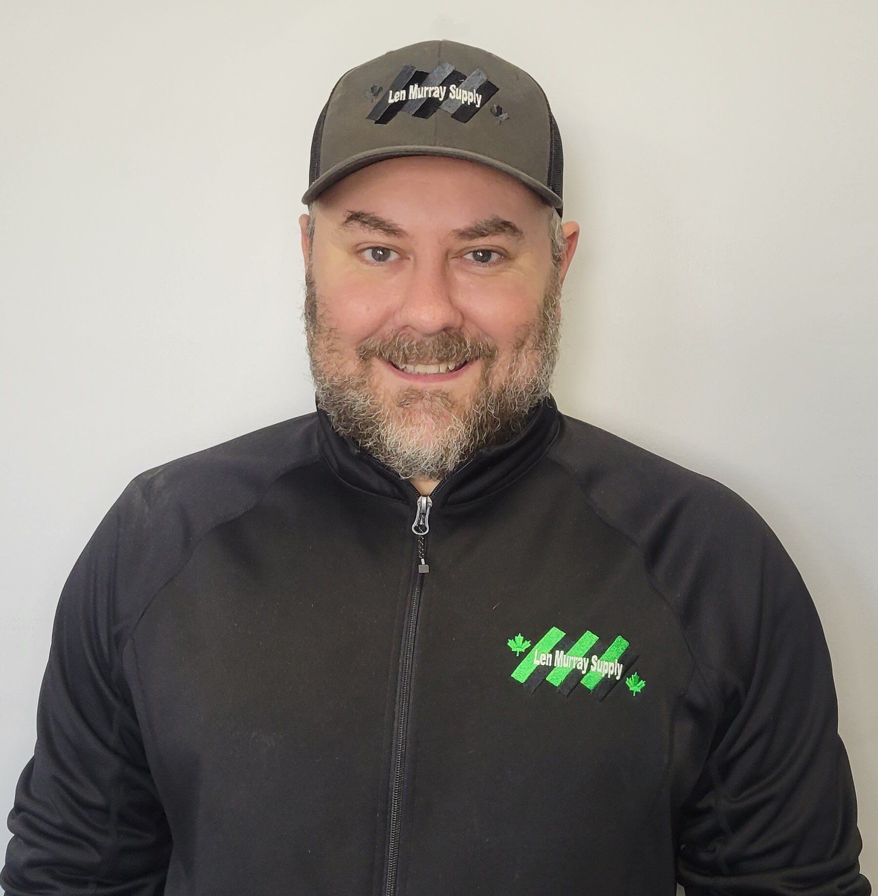 A man with a beard wearing a hat and a black jacket