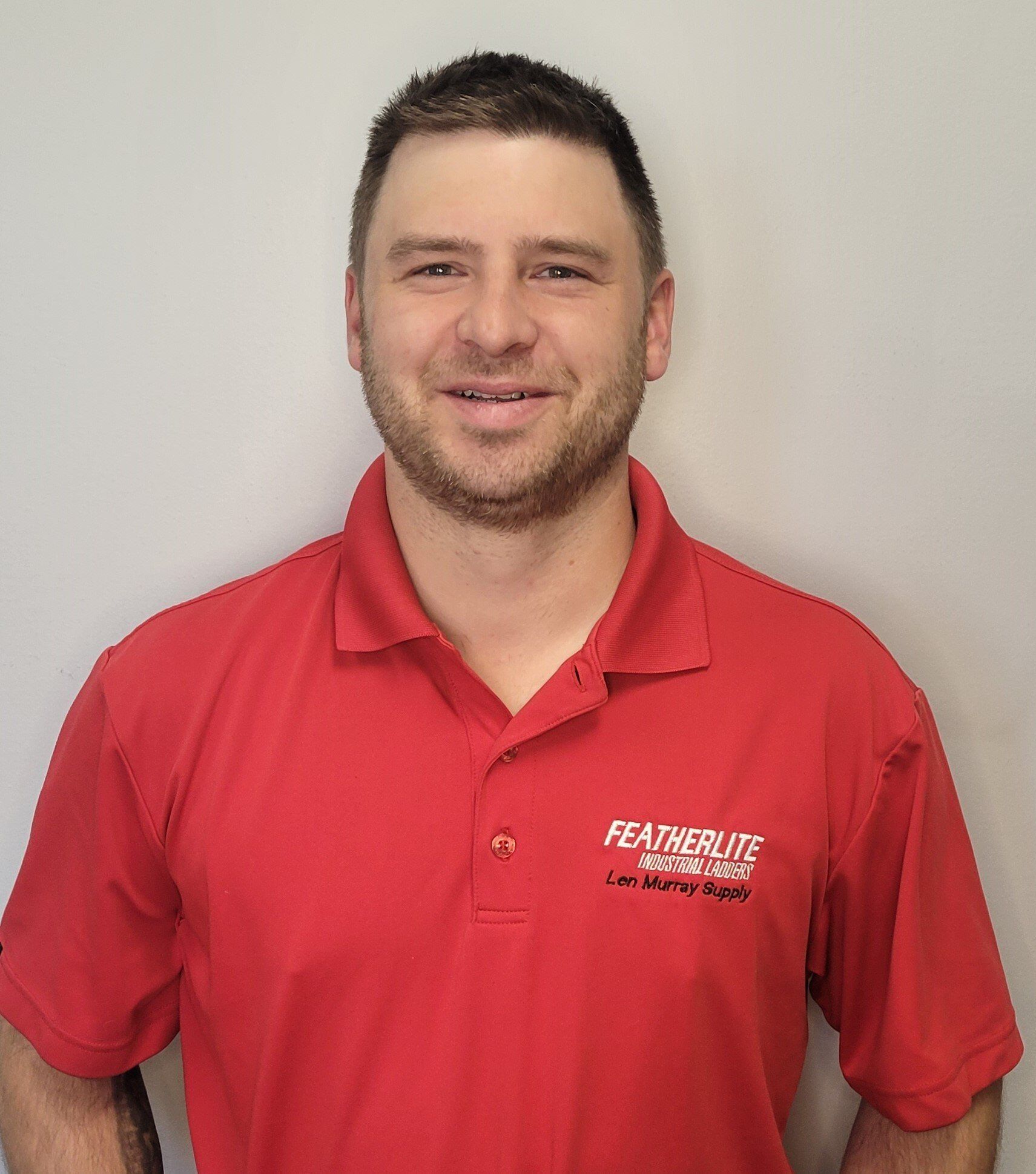 A man wearing a red polo shirt is smiling for the camera.