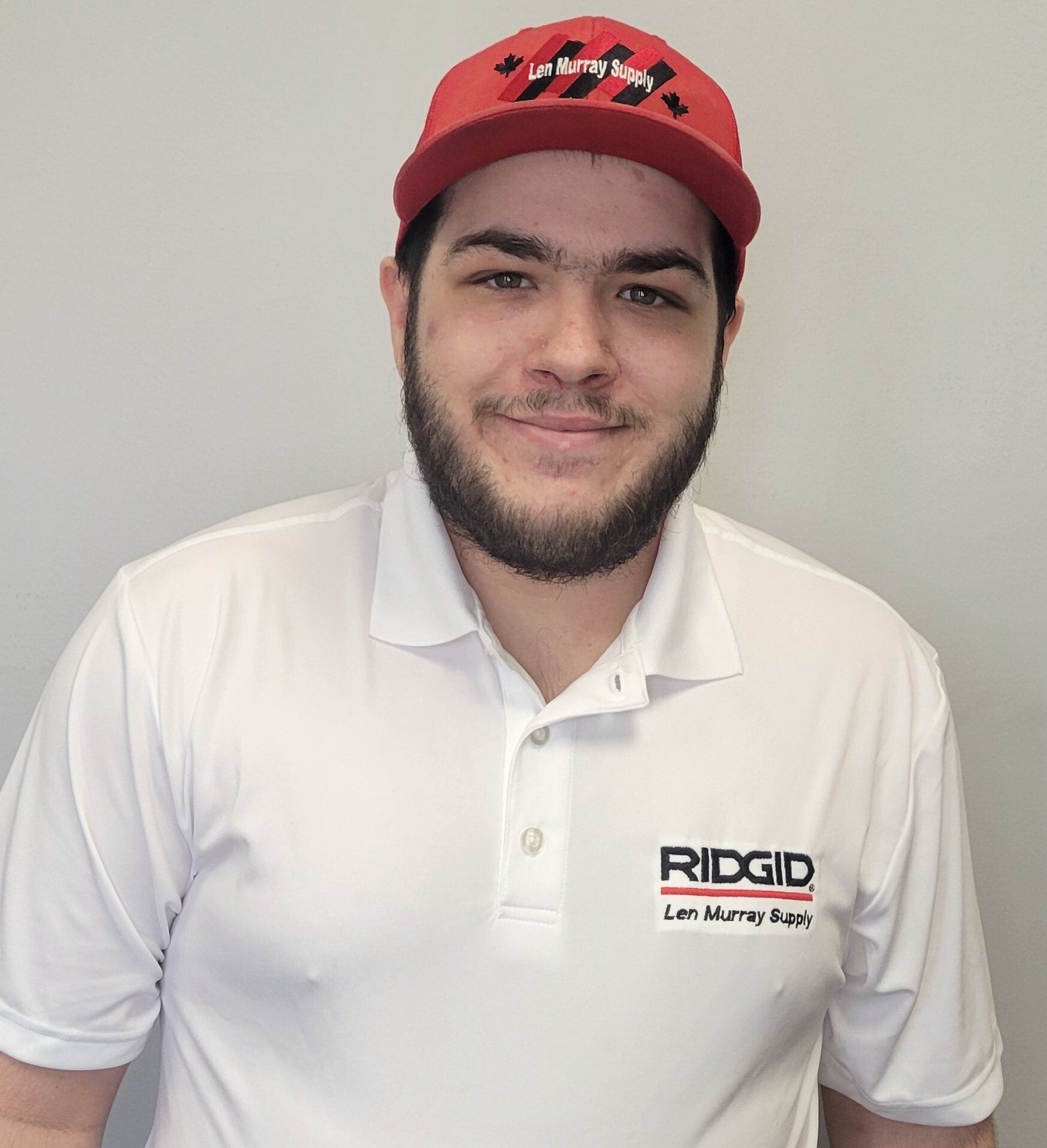 A man wearing a red hat and a white shirt with the word ridgid on it.