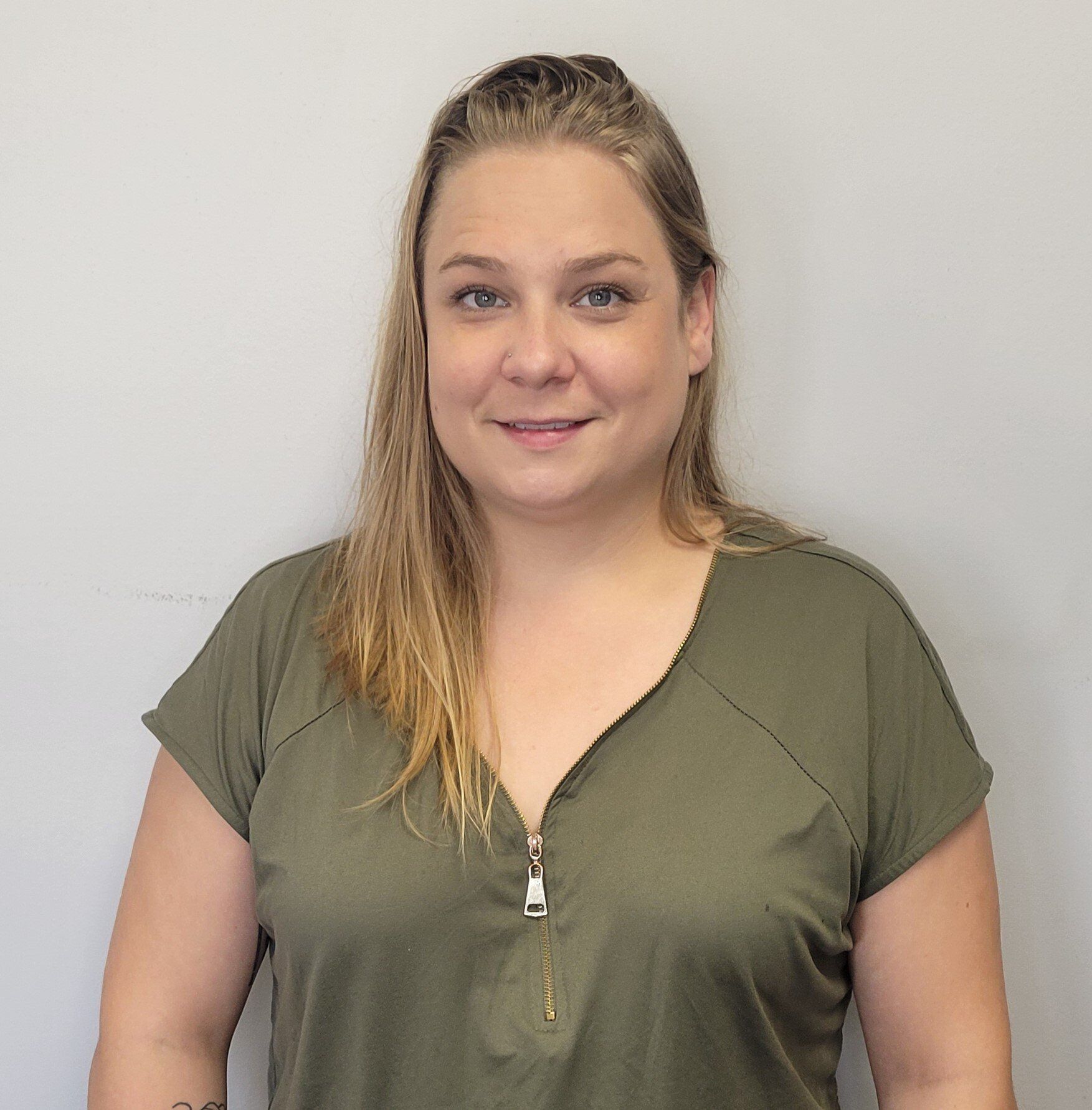 The woman is wearing a green shirt with a zipper on the front.