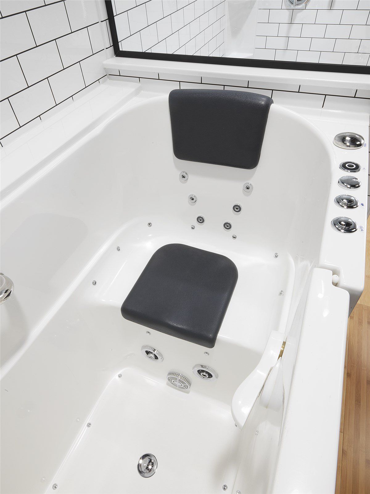 White walk-in bathtub with a gray seat and headrest.  Jet controls on the right.  Bathroom setting, angled view.