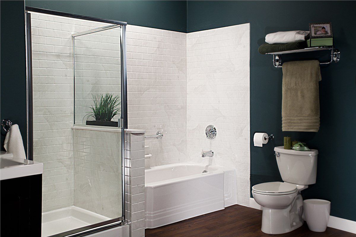 A bathroom with a bathtub, shower, and toilet. The walls are teal and white, with a dark wood floor.