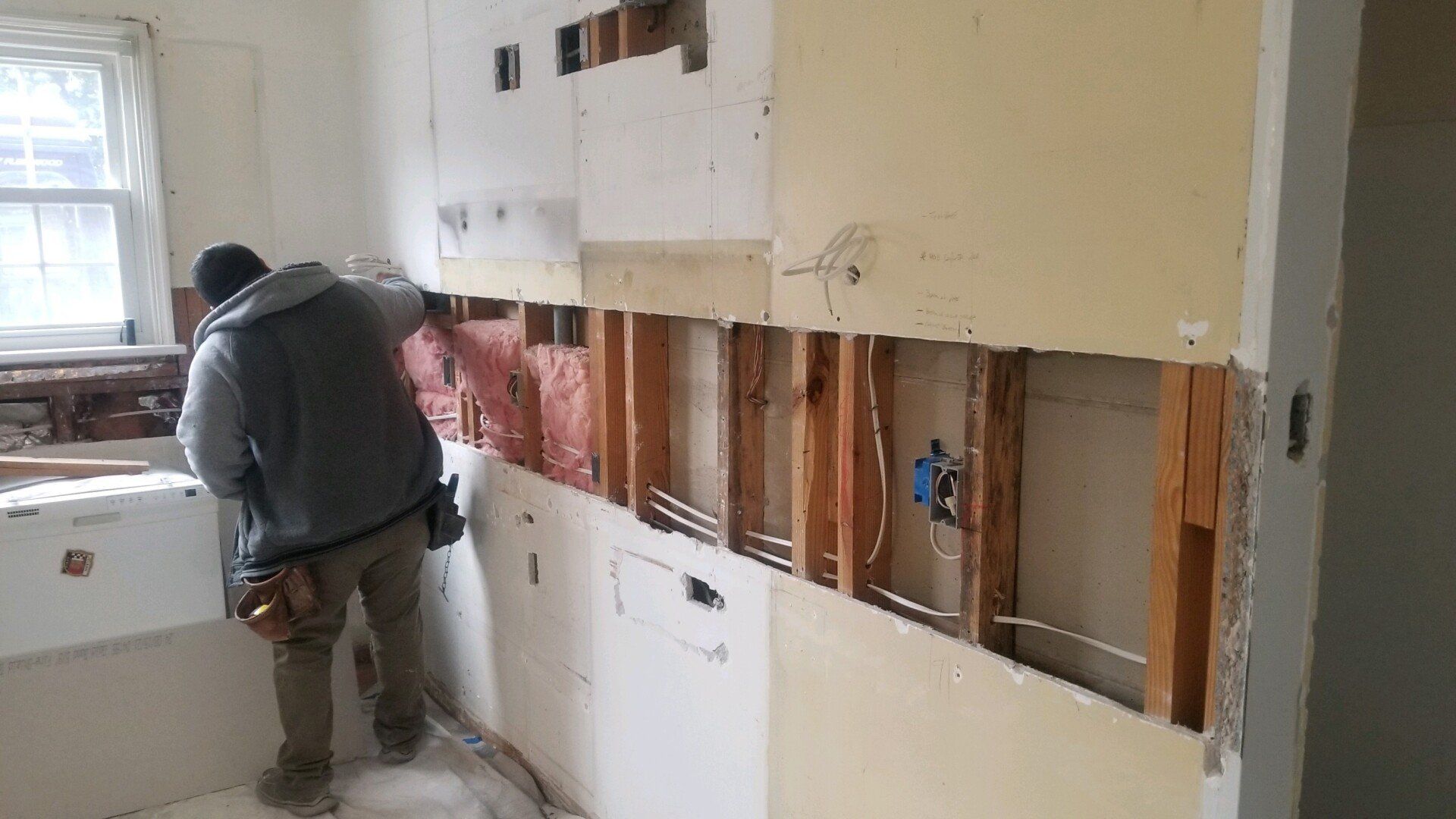 a man in a gray hoodie is working on a wall