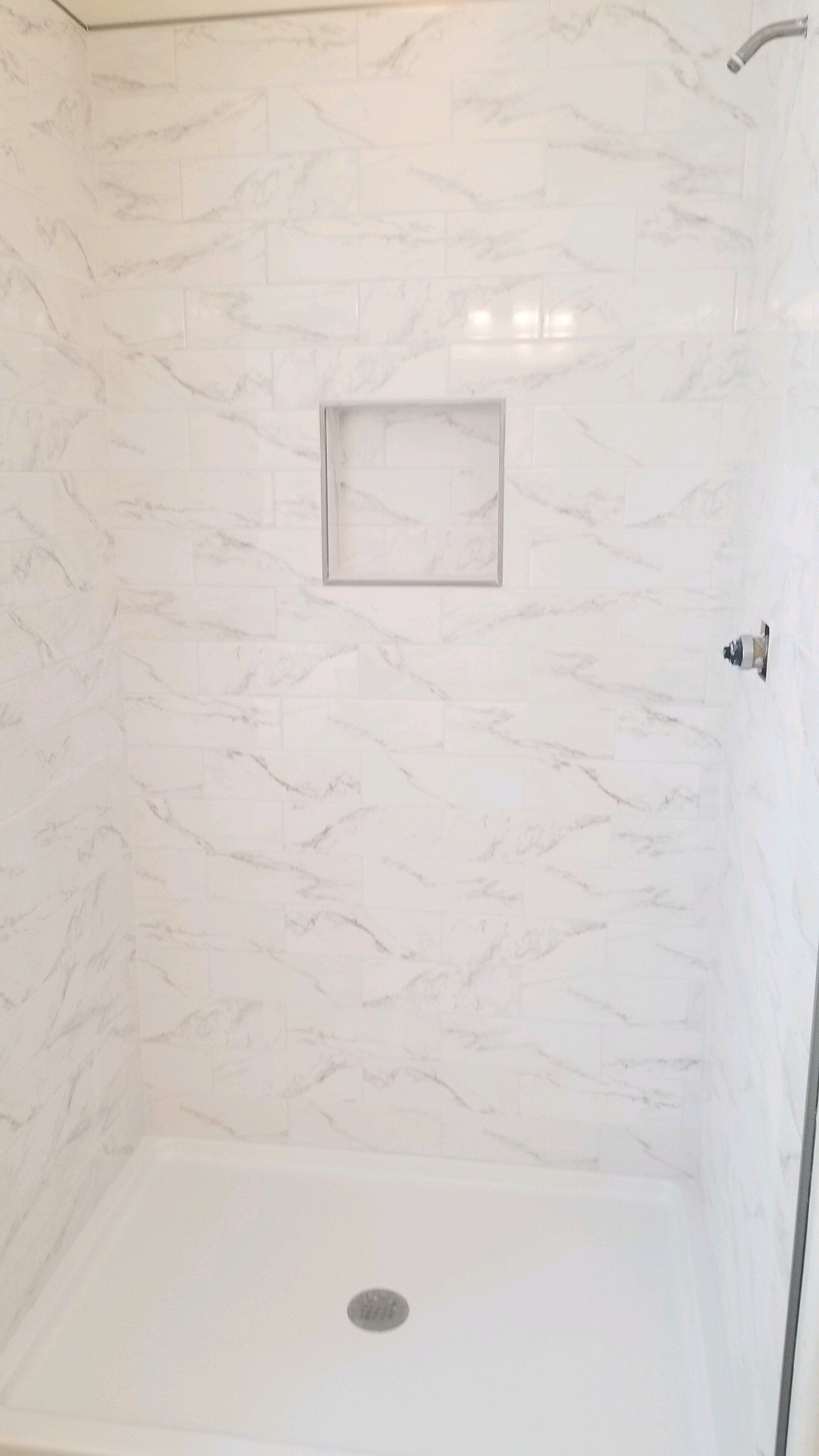 a shower stall with white tiles and a shower head