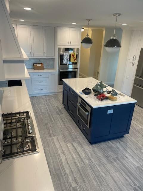 a kitchen with white cabinets , stainless steel appliances , and a large blue island .