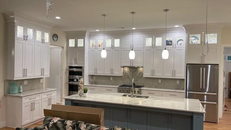 a kitchen with white cabinets , stainless steel appliances , and a large island .
