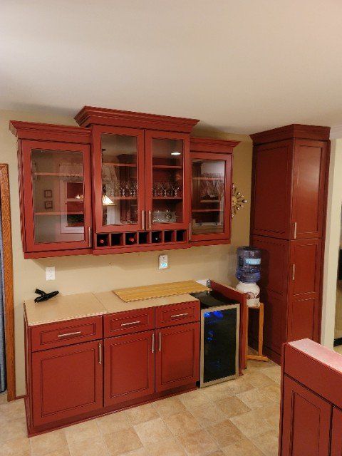 a kitchen with red cabinets and a wine cooler