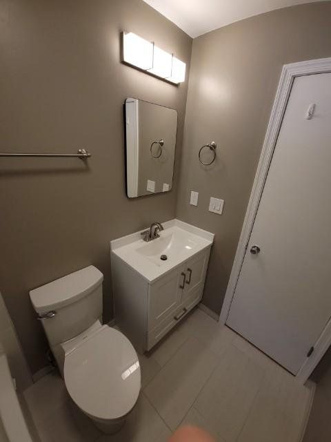 a bathroom with a toilet , sink and mirror .