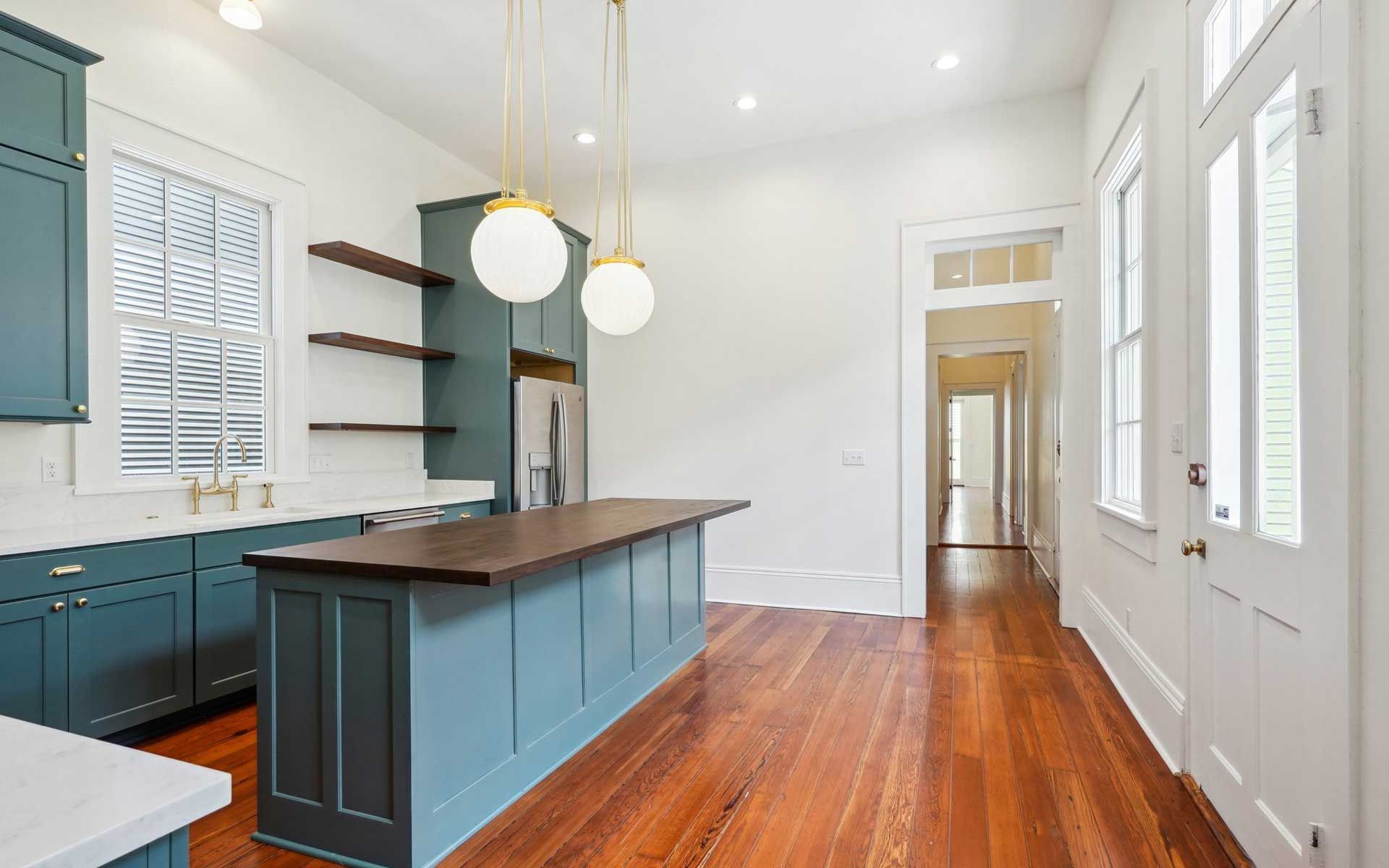A kitchen with blue cabinets , hardwood floors , and a large island.