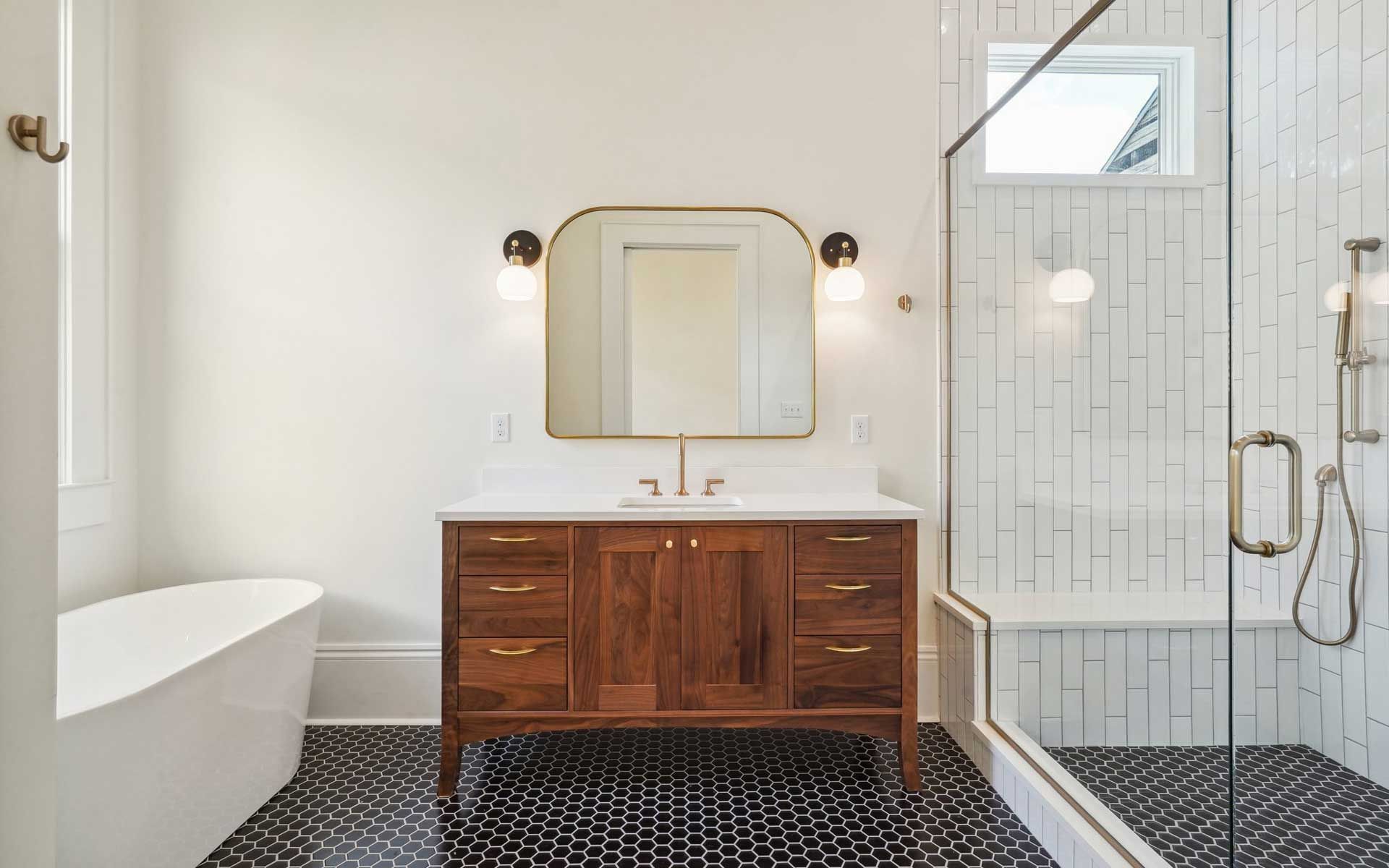 A bathroom with a tub , sink , mirror and shower.