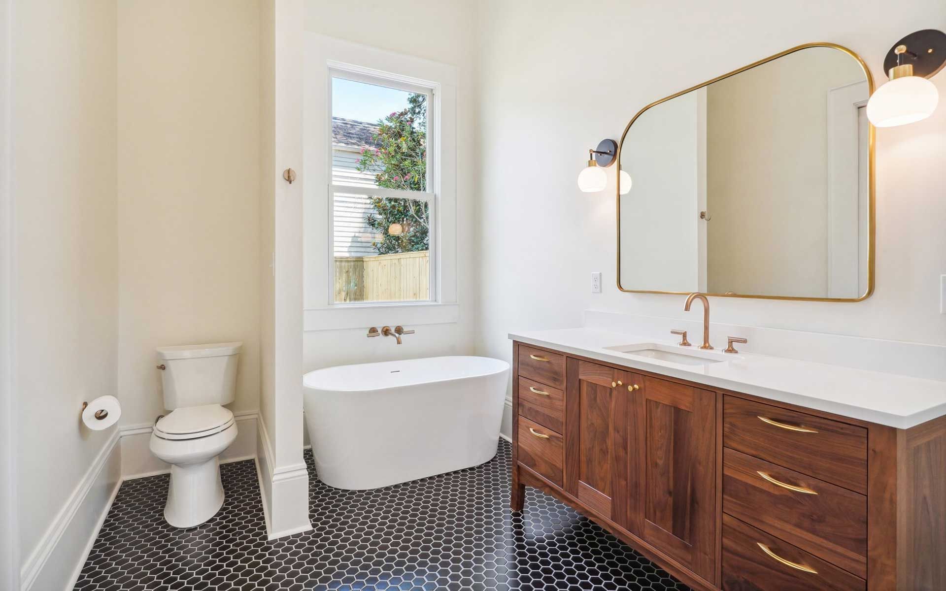 A bathroom with a tub , toilet , sink and mirror.