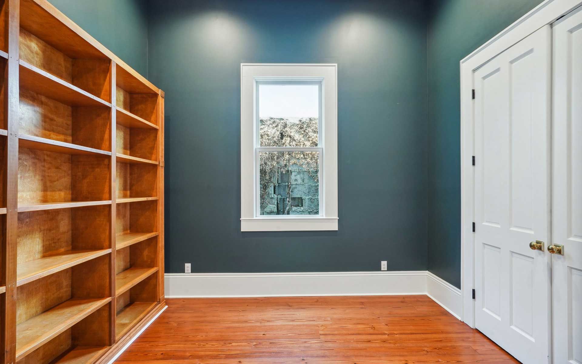 An empty room with wooden shelves and a window.