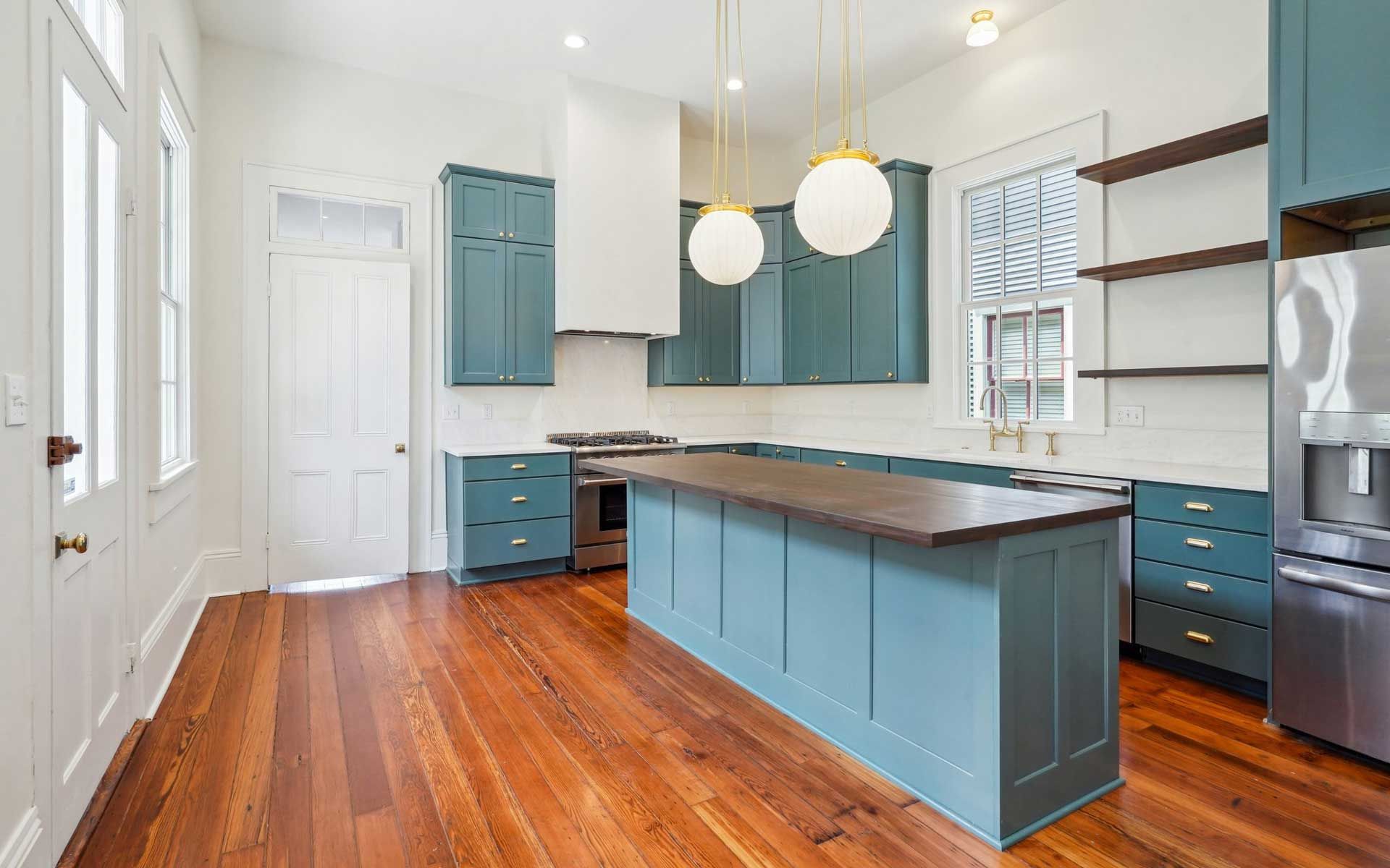A kitchen with blue cabinets and hardwood floors.