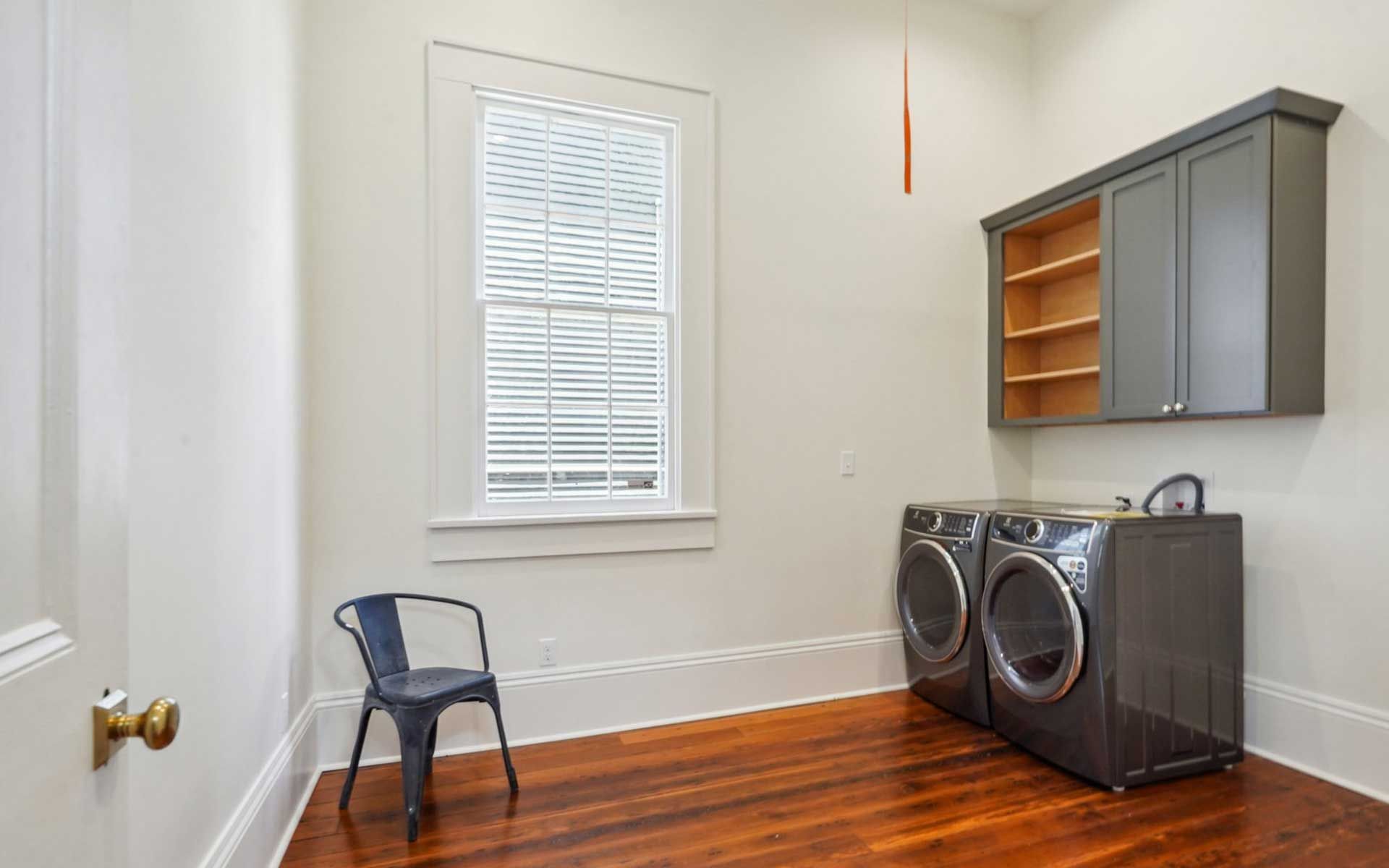 A laundry room with a washer and dryer and a chair.