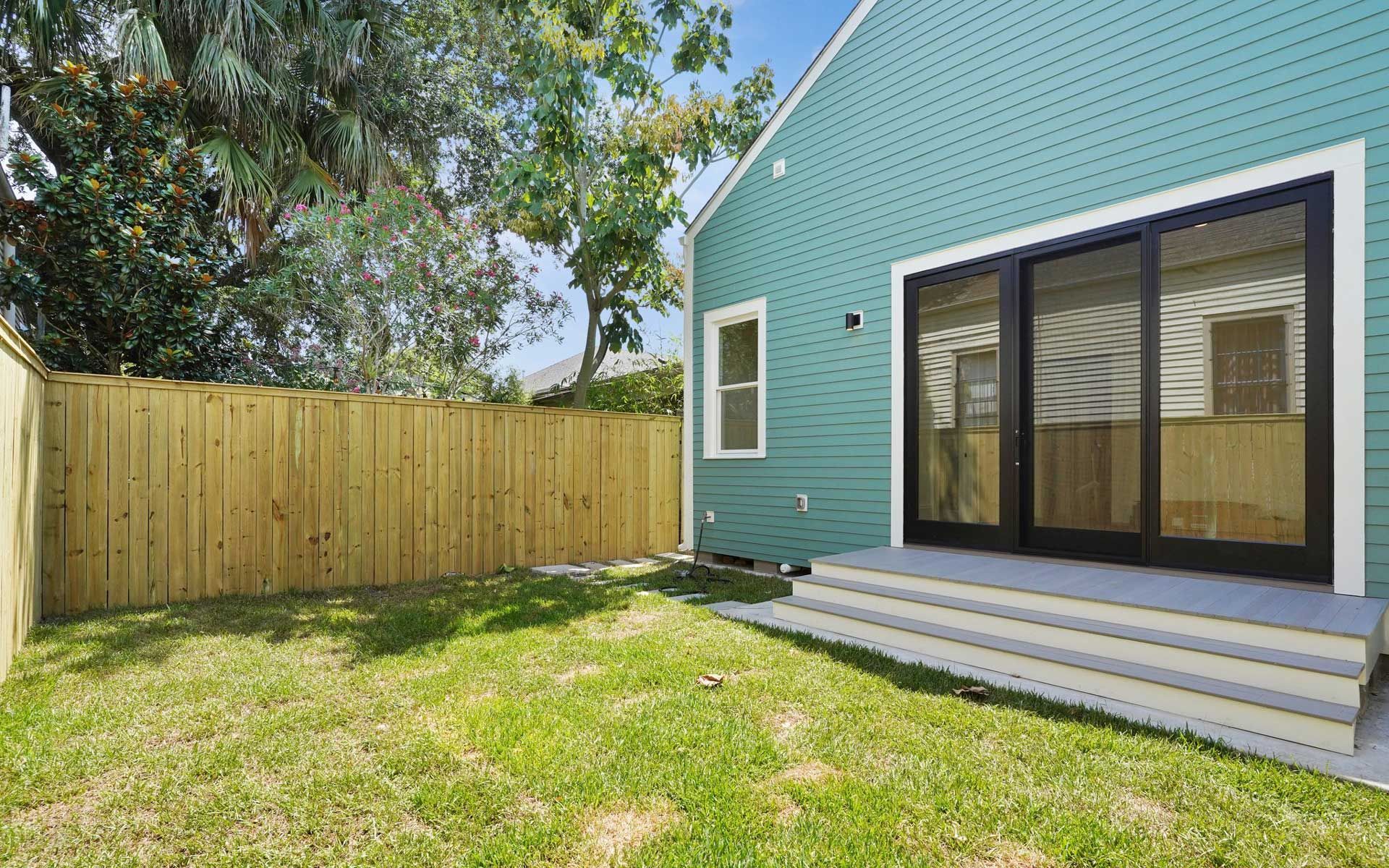 The backyard of a house with a wooden fence and sliding glass doors.
