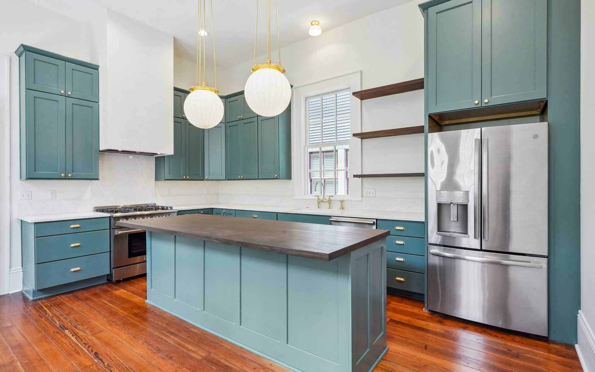A kitchen with blue cabinets , stainless steel appliances , and a large island.