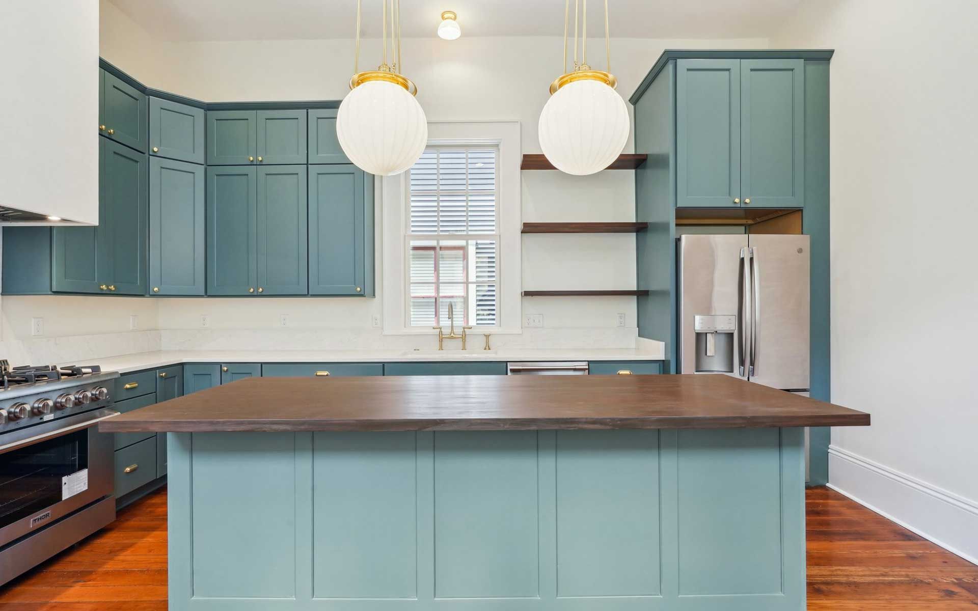 A kitchen with blue cabinets and a large island in the middle.