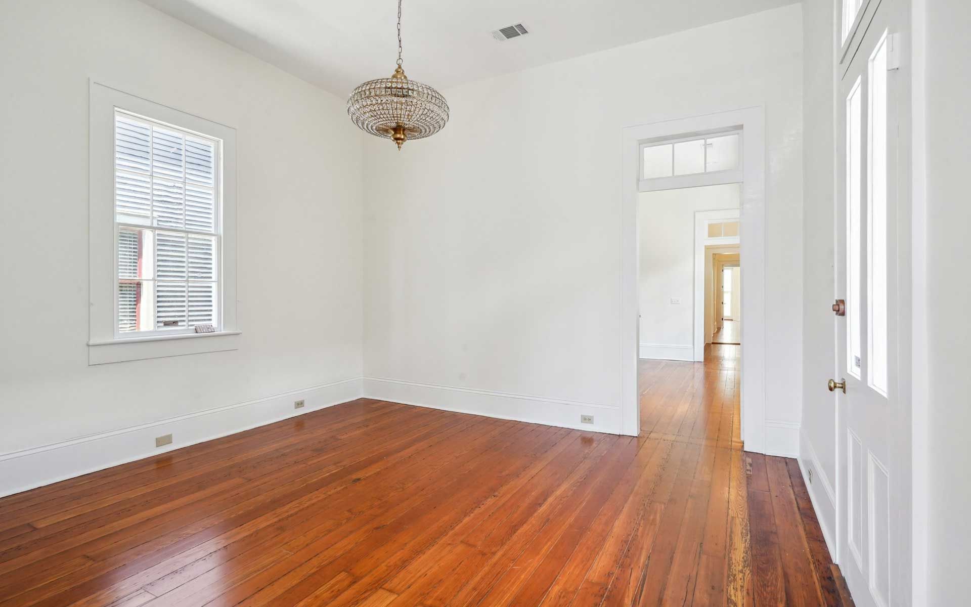 An empty room with hardwood floors and white walls.