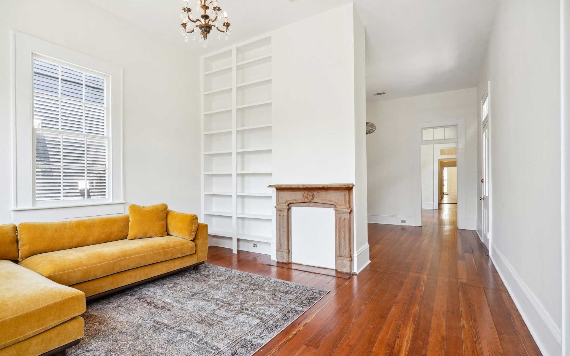 A living room with a yellow couch and a fireplace.