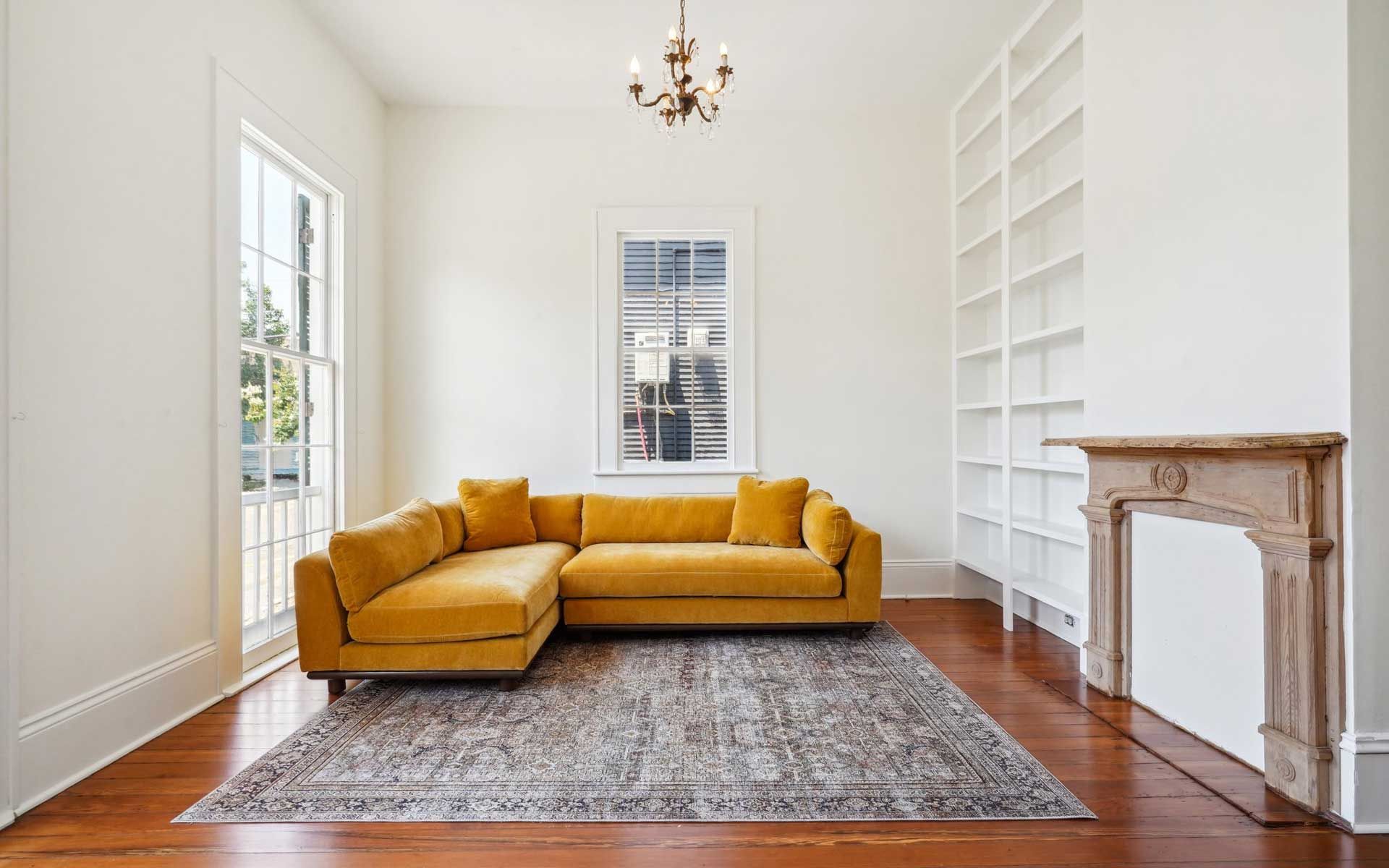A living room with a yellow sectional couch and a fireplace.