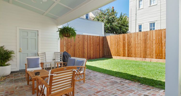 There is a patio with a table and chairs and a wooden fence in the backyard.