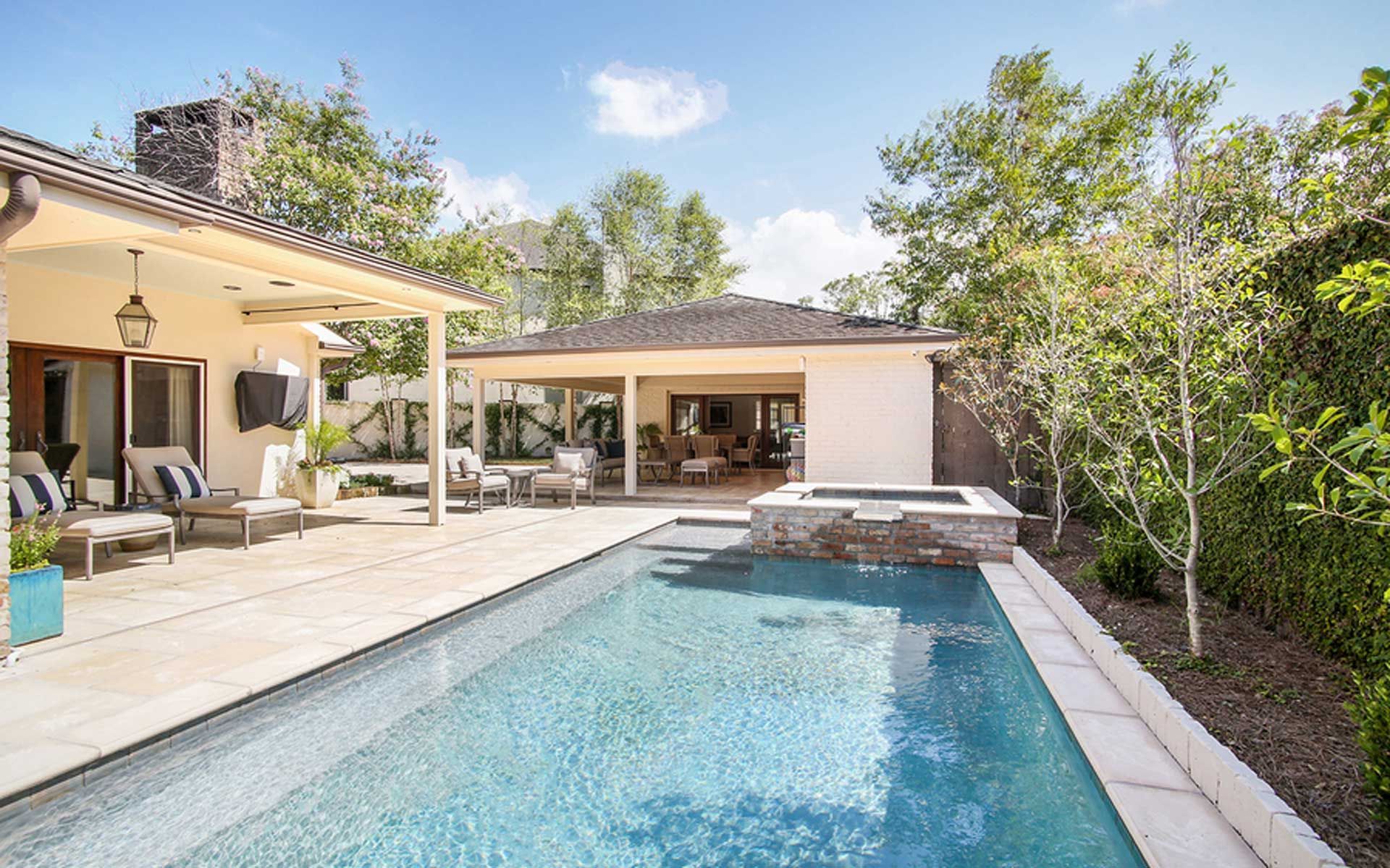 There is a large swimming pool in the backyard of a house.