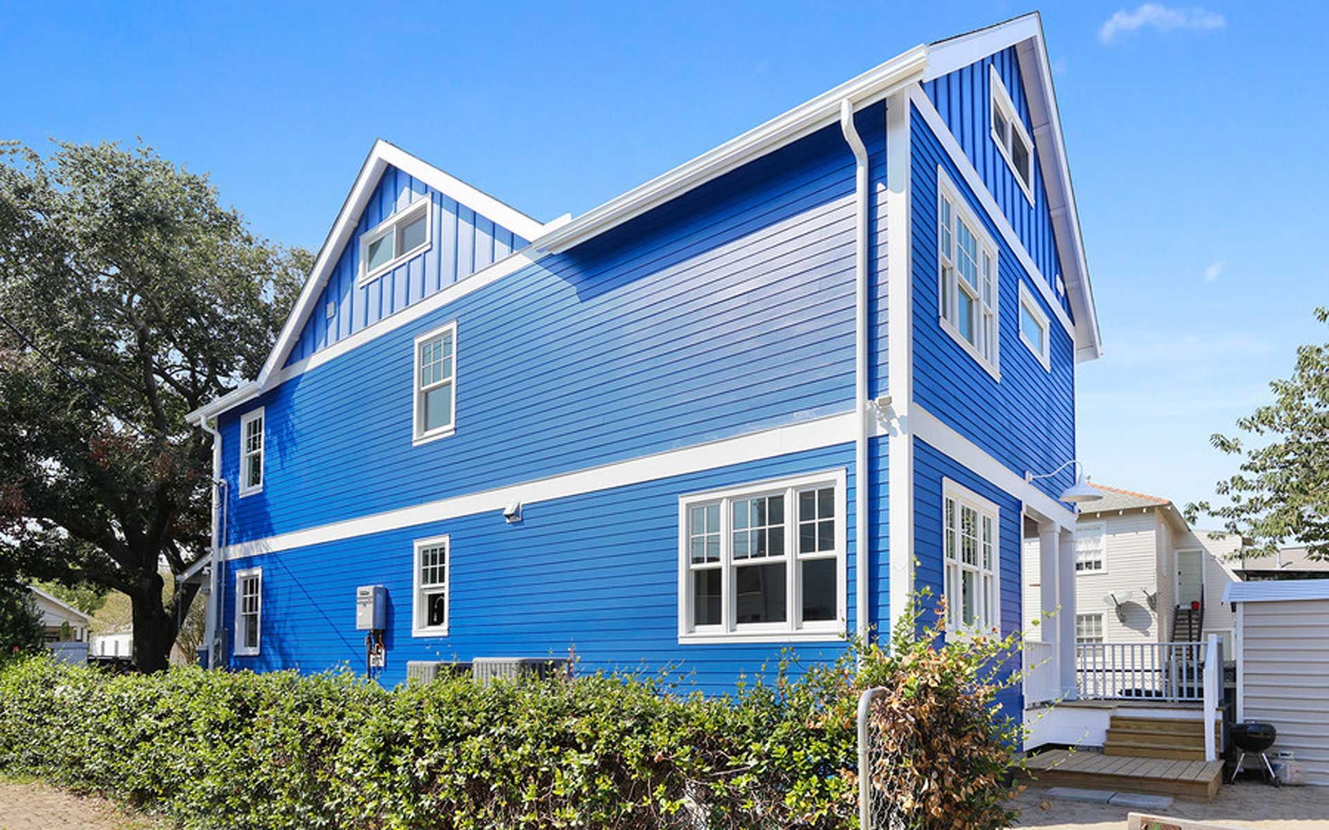 A blue and white house with a lot of windows and a garage.