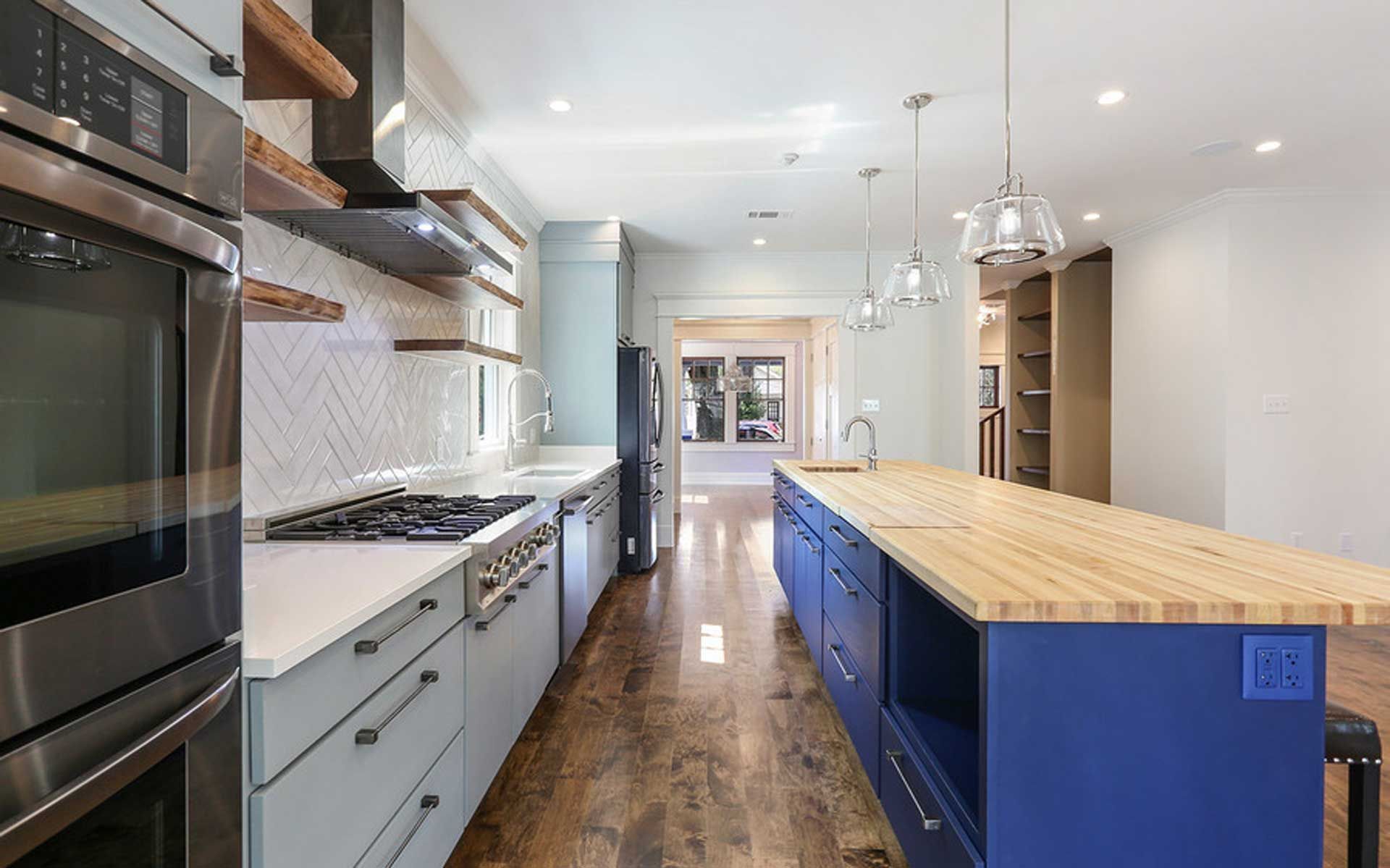 A kitchen with blue cabinets , wooden counter tops , stainless steel appliances and a large island.