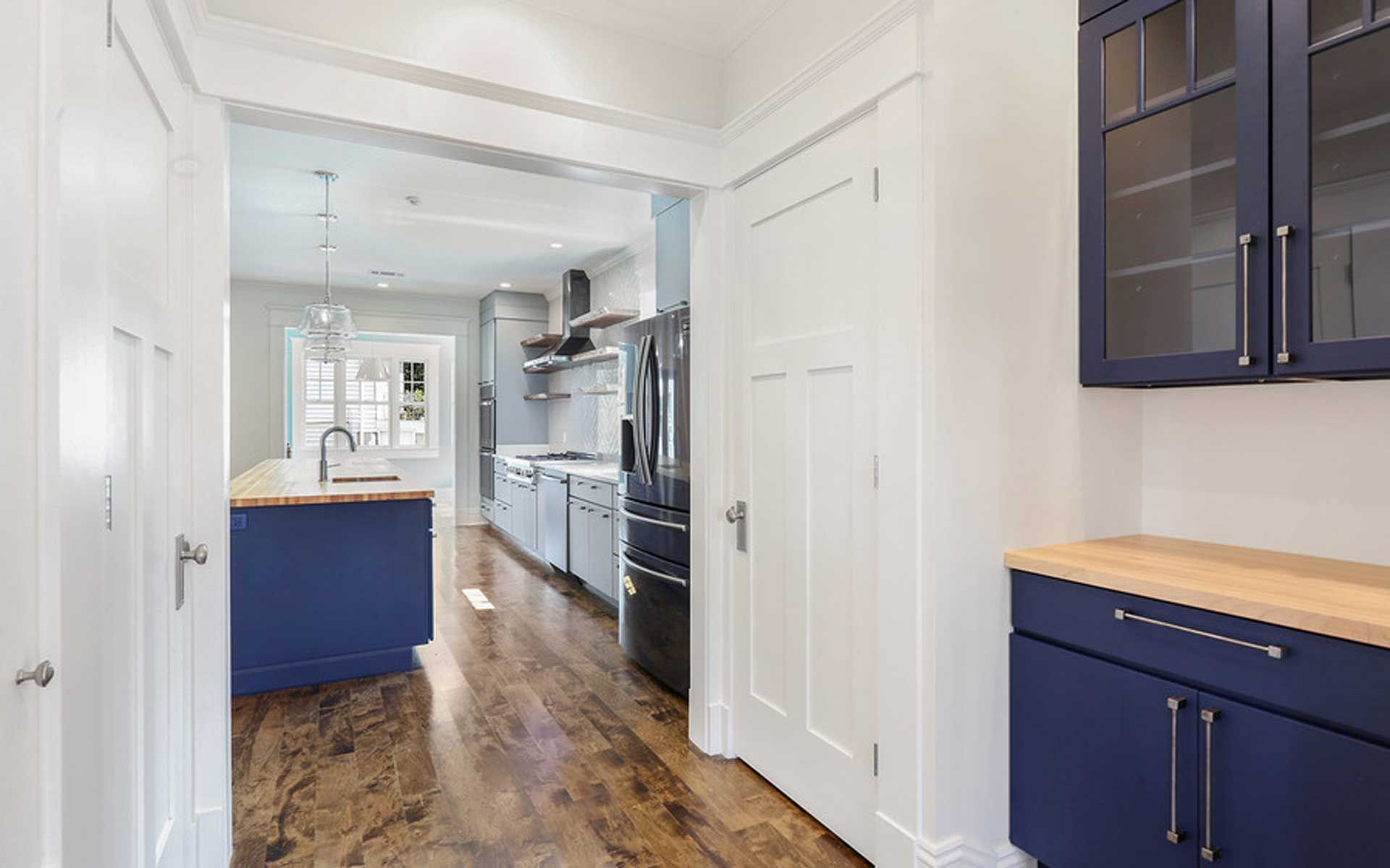 A kitchen with blue cabinets and hardwood floors in a house.